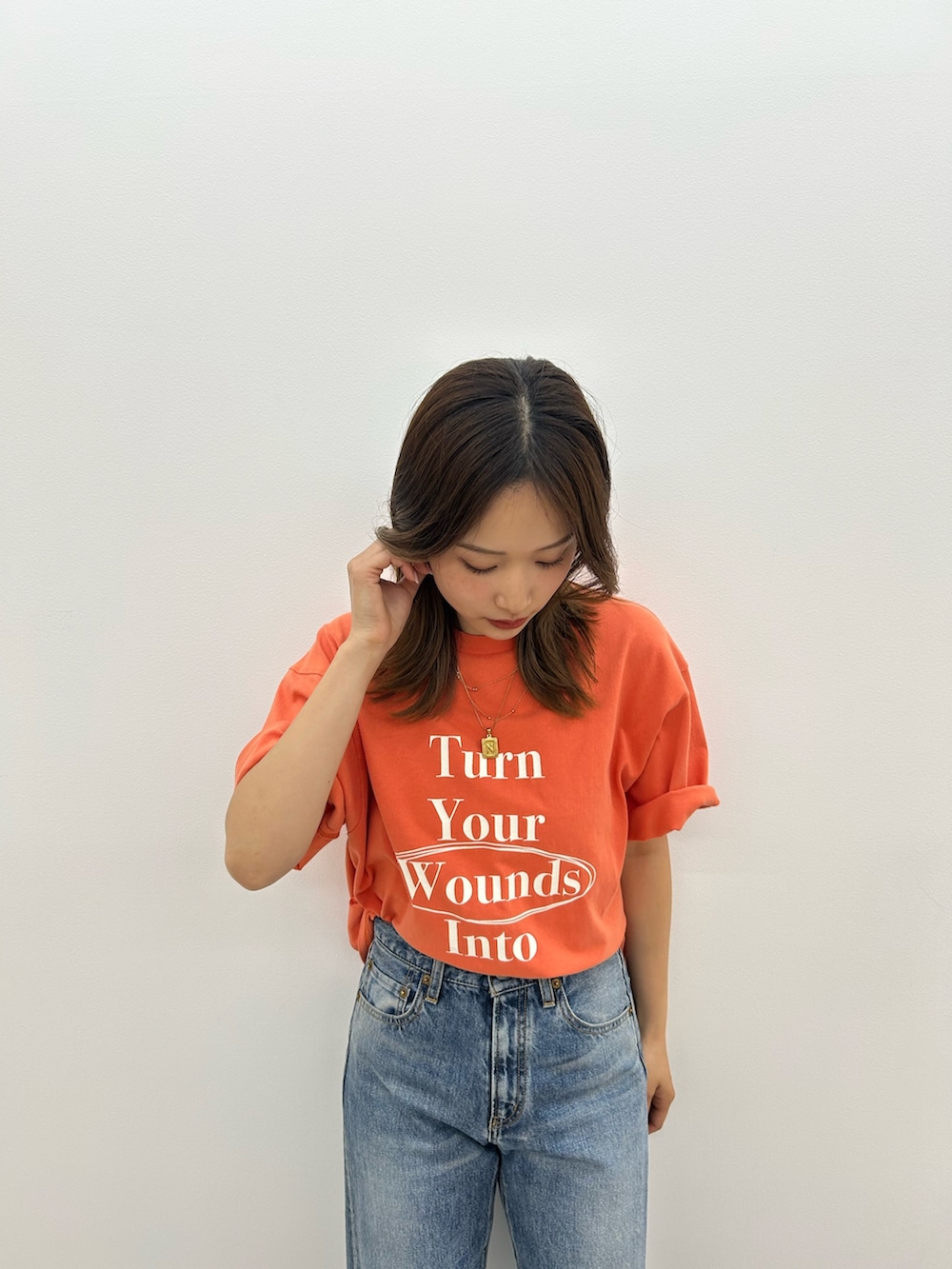 ブルー系のデニムパンツ、オレンジ系のTシャツ/カットソー、ブラック系のサンダルを着用したレディースの春コーディネートの7枚目の写真