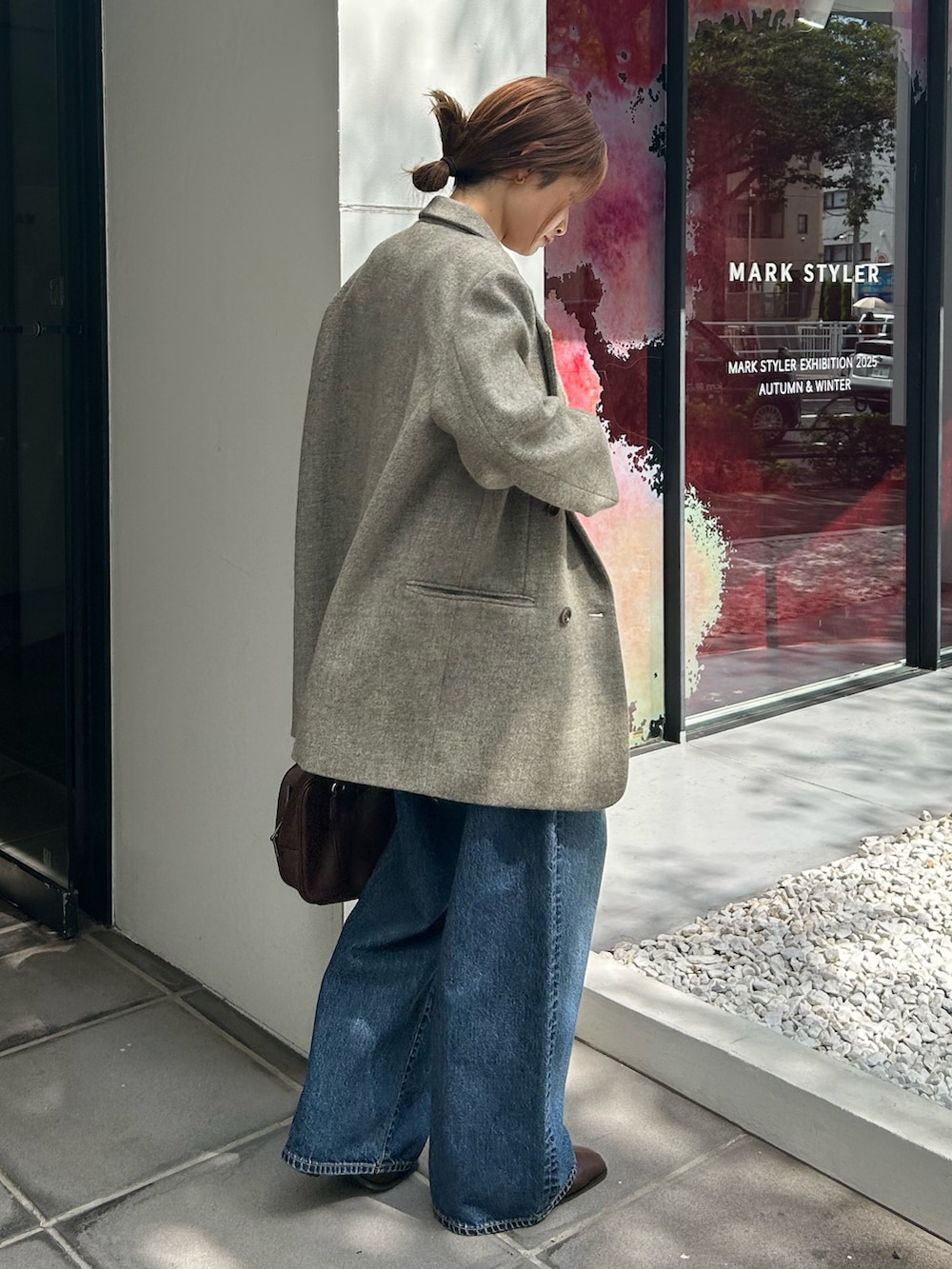 グレー系のテーラードジャケット、ホワイト系のニット/セーター、ブルー系のデニムパンツを着用したレディースの秋コーディネートの5枚目の写真