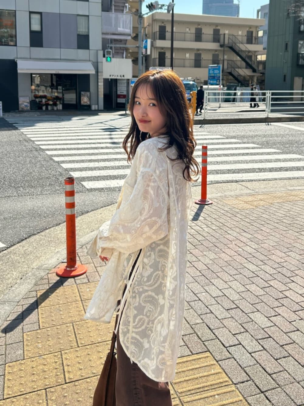 ブラウン系のキャミソール、ホワイト系のシャツ/ブラウス、ブラウン系のデニムパンツを着用したレディースの春コーディネートの7枚目の写真