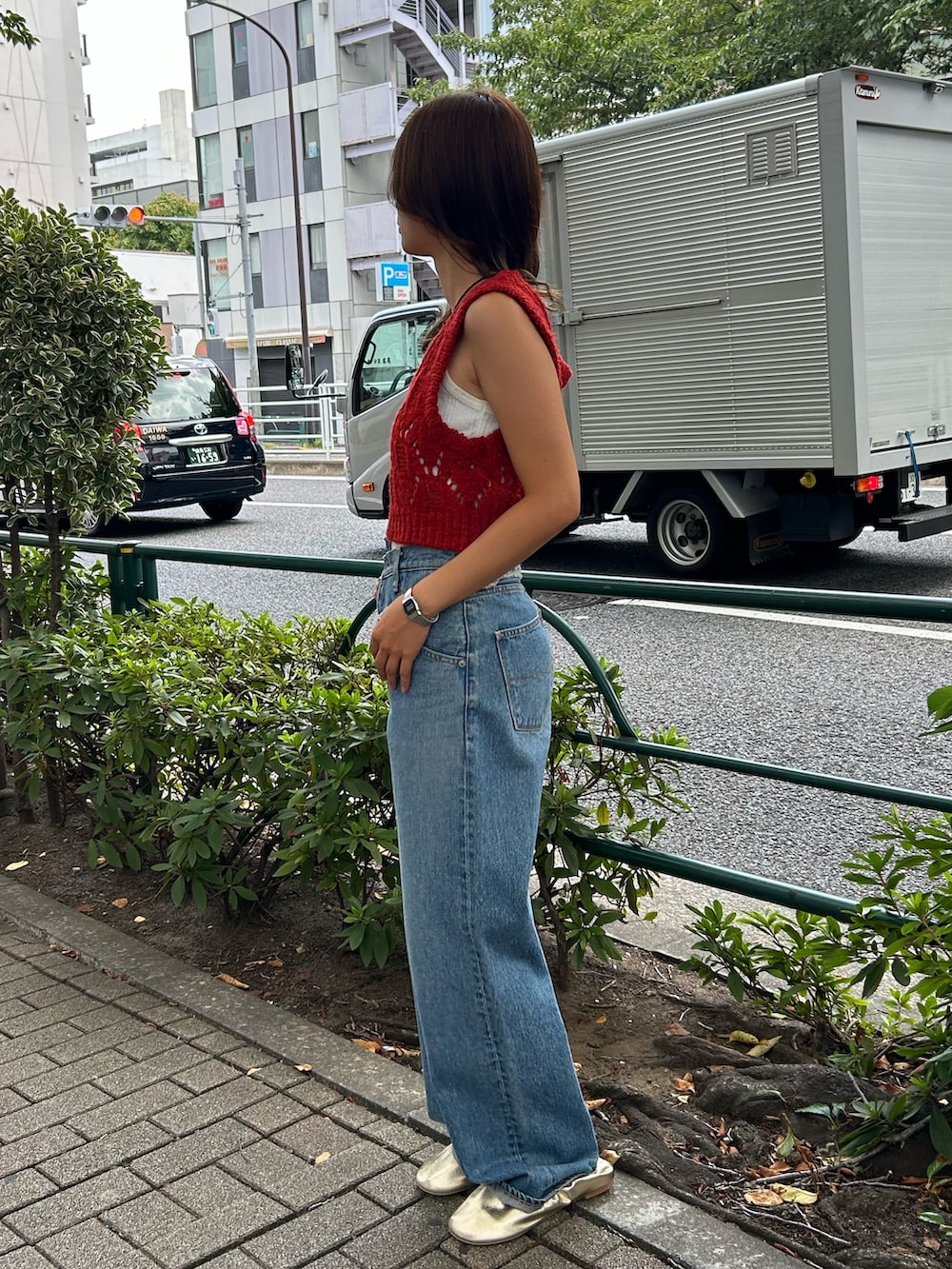 ブルー系のデニムパンツ、ゴールド系のバレエシューズ、オレンジ系のワンピースを着用したレディースの夏コーディネートの3枚目の写真