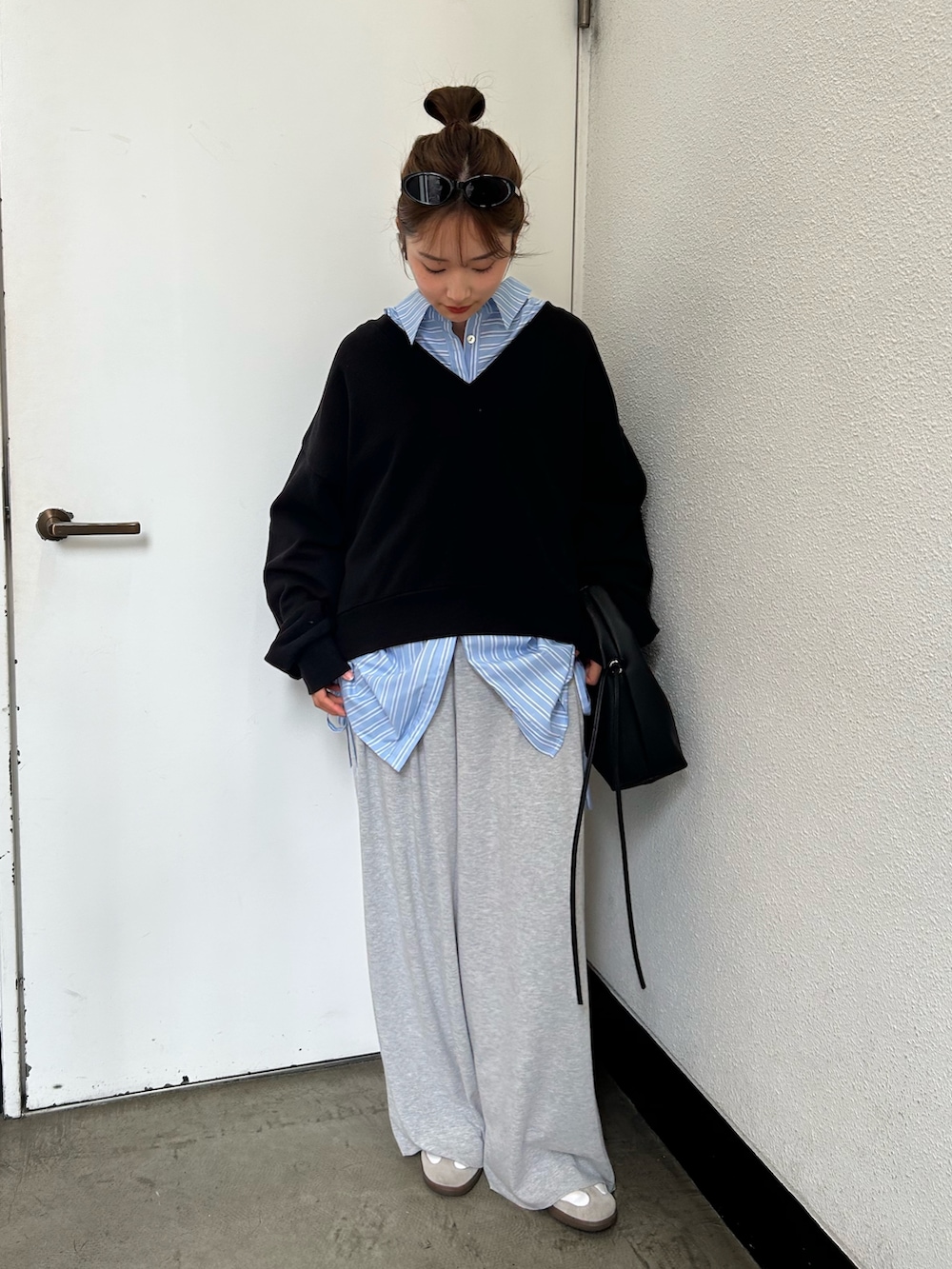 ブラック系のスウェット、ブルー系のシャツ/ブラウス、ブラック系のハンドバッグを着用したレディースの春コーディネートの2枚目の写真