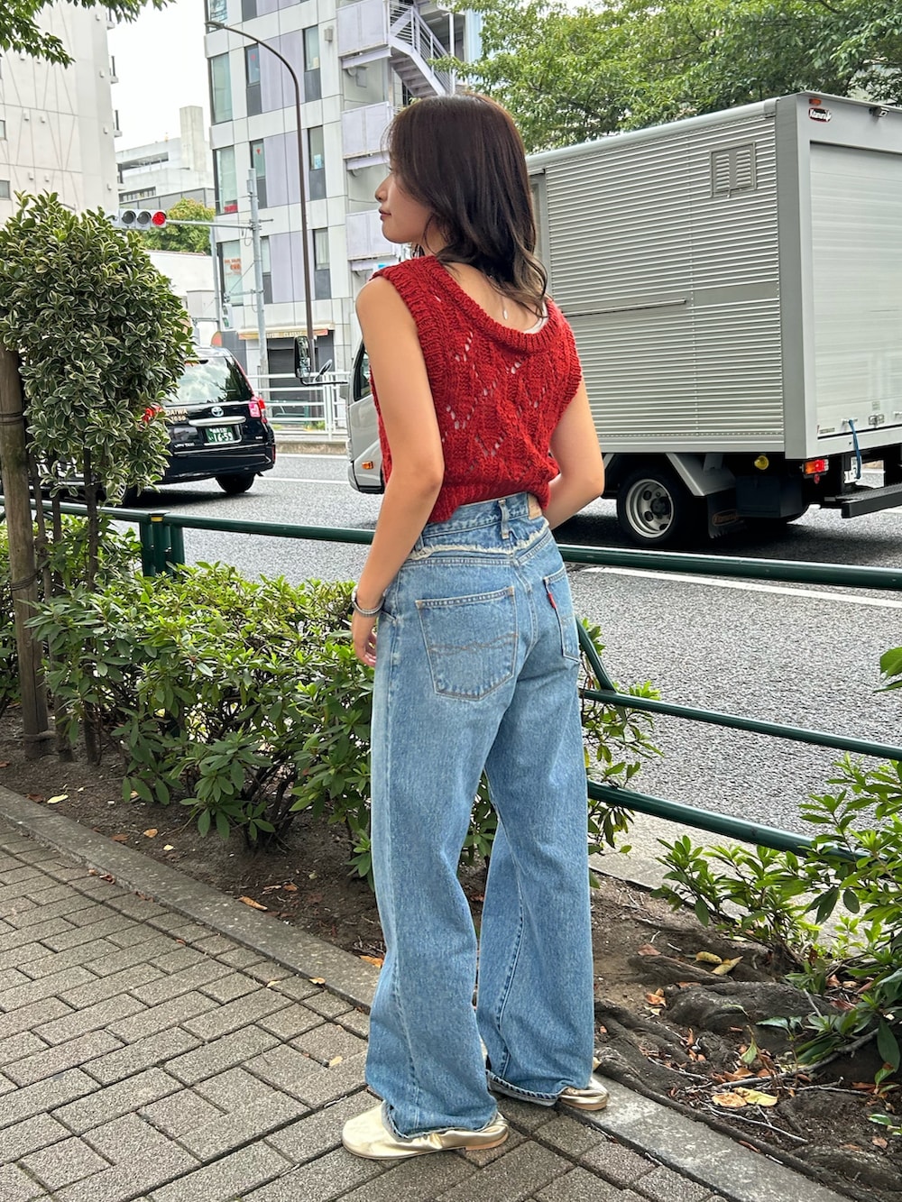 ブルー系のデニムパンツ、ゴールド系のバレエシューズ、オレンジ系のワンピースを着用したレディースの夏コーディネートの2枚目の写真