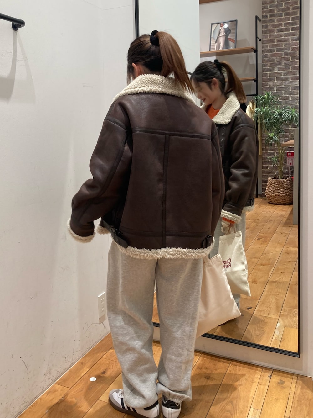 グレー系のスウェットパンツ、レッド系のトートバッグ、ブラウン系のブルゾンを着用したレディースの冬コーディネートの3枚目の写真