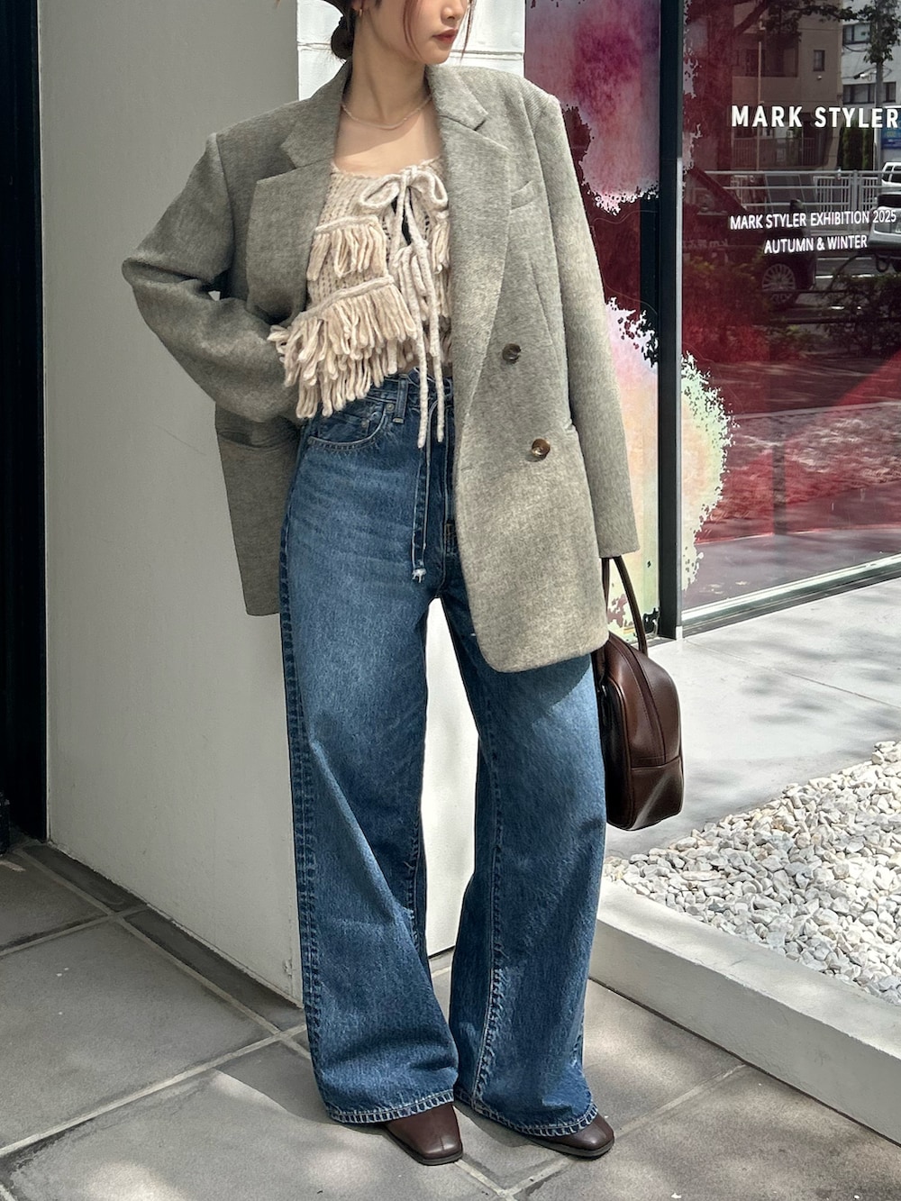 グレー系のテーラードジャケット、ホワイト系のニット/セーター、ブルー系のデニムパンツを着用したレディースの秋コーディネートの7枚目の写真