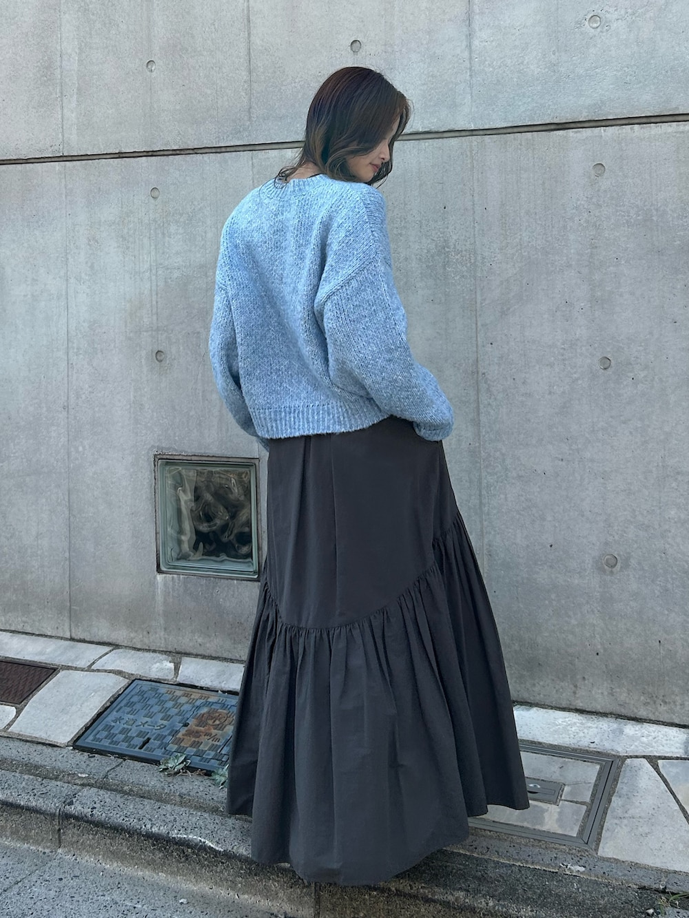 グレー系のスカート、ブラック系のネックレスを着用したレディースの秋コーディネートの3枚目の写真