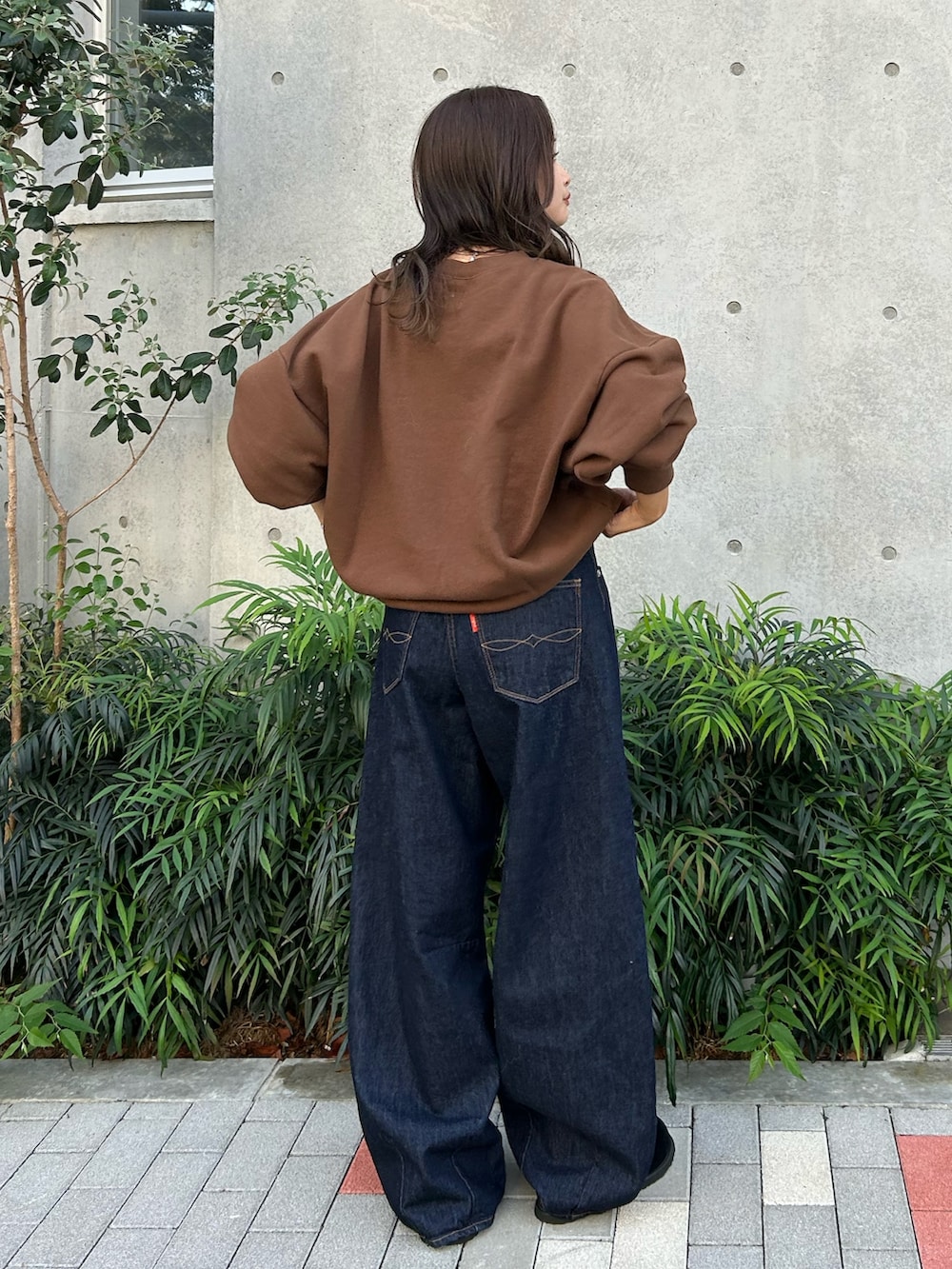 ブルー系のデニムパンツ、ブラック系のスリッポン、ブラウン系のスウェットを着用したレディースの冬コーディネートの4枚目の写真