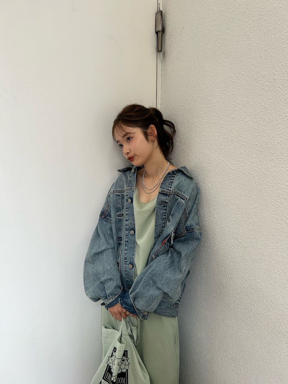 グリーン系のトートバッグ、ブルー系のスニーカー、ブルー系のデニムジャケットを着用したレディースの春コーディネートの5枚目の写真