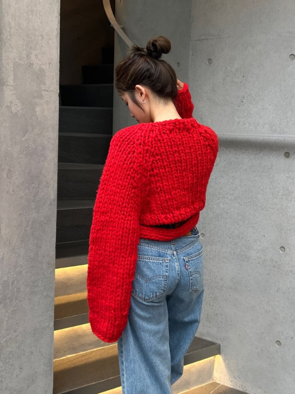 ブルー系のデニムパンツ、レッド系のニット/セーターを着用したレディースの秋コーディネートの6枚目の写真