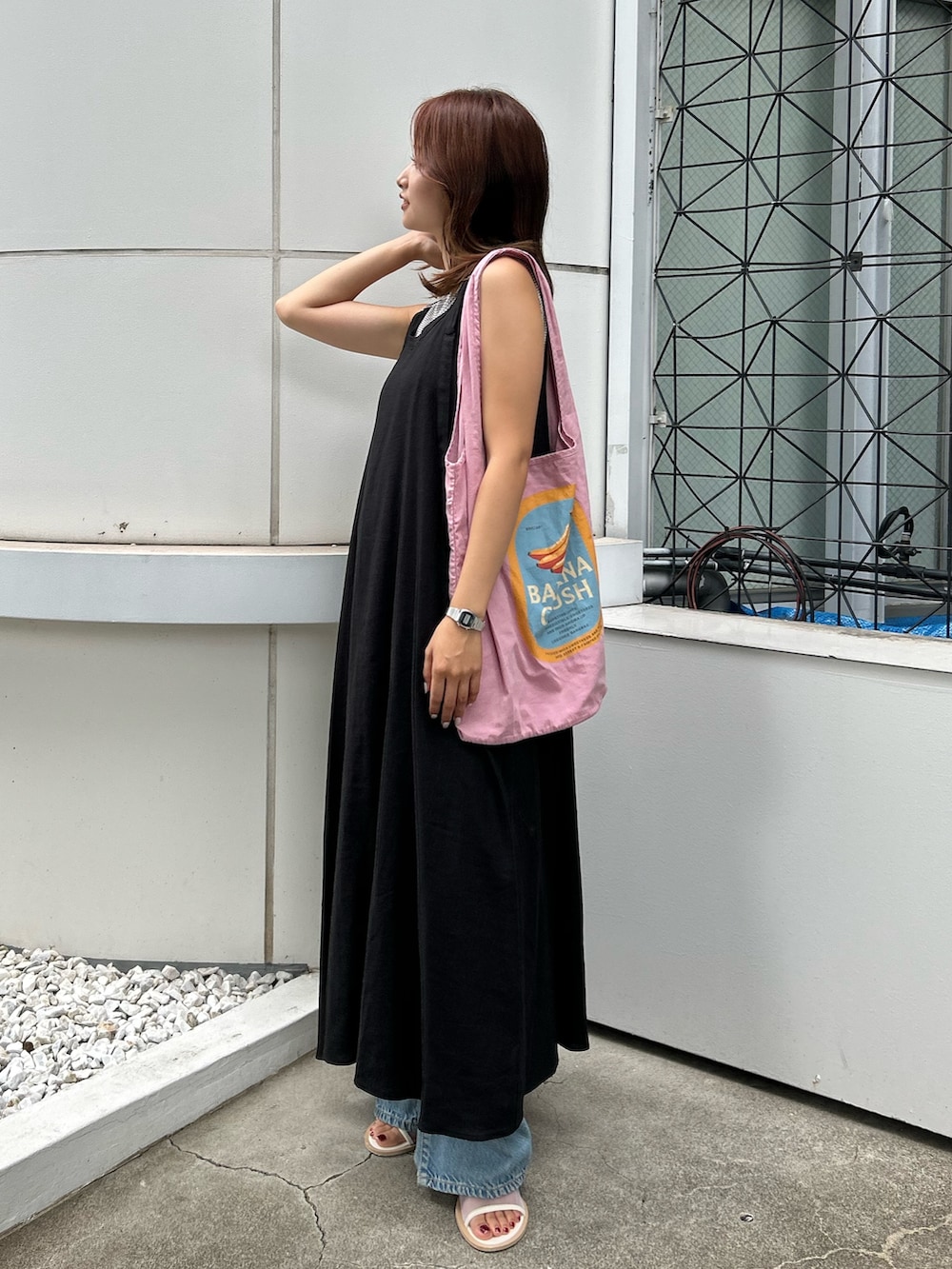 ブラック系のワンピース、ホワイト系のサンダル、ブルー系のデニムパンツを着用したレディースの夏コーディネートの3枚目の写真