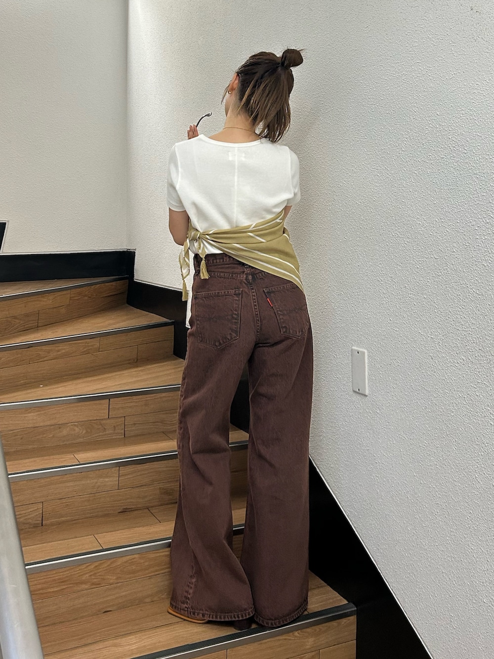 ブラウン系のデニムパンツ、ホワイト系のTシャツ/カットソー、イエロー系のバンダナ/スカーフを着用したレディースの春コーディネートの3枚目の写真