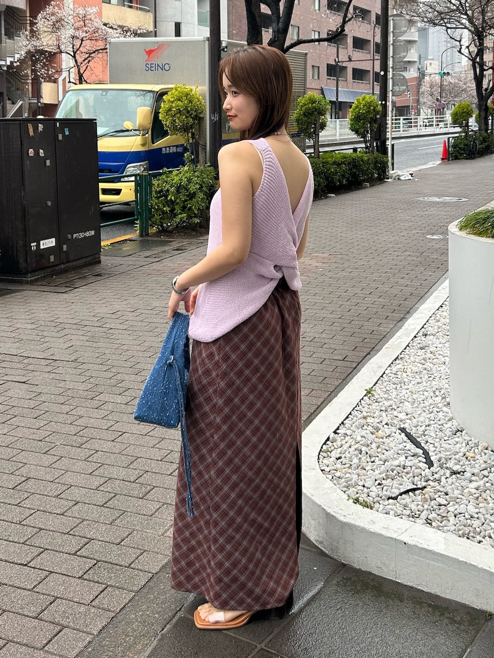 ブルー系のハンドバッグ、ブラウン系のスカート、シルバー系のネックレスを着用したレディースの春コーディネートの2枚目の写真