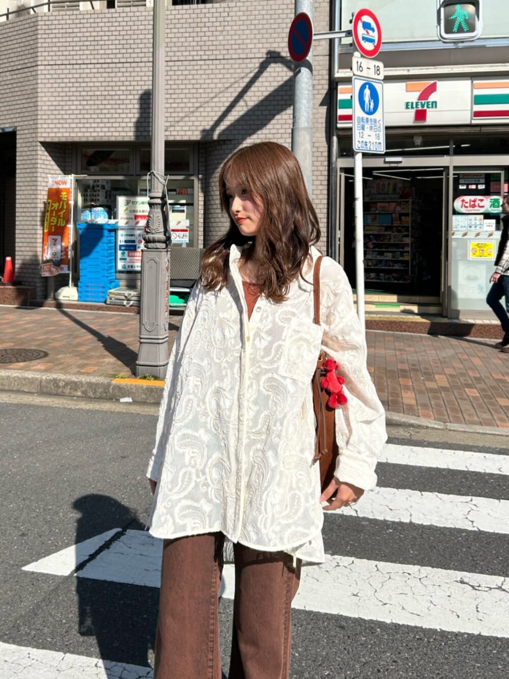 ブラウン系のキャミソール、ホワイト系のシャツ/ブラウス、ブラウン系のデニムパンツを着用したレディースの春コーディネートの3枚目の写真