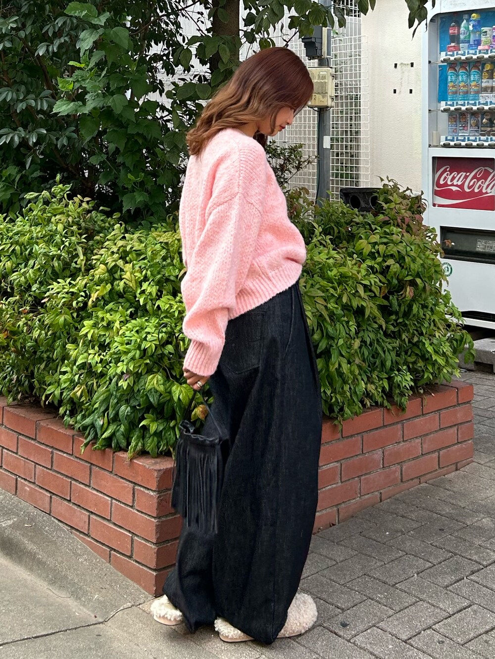 ピンク系のニット/セーター、ブラック系のデニムパンツ、ブラック系のショルダーバッグを着用したレディースの秋コーディネートの3枚目の写真