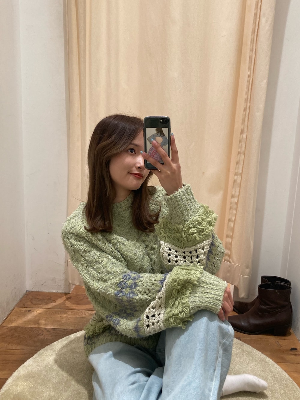 グリーン系のニット/セーター、ブルー系のデニムパンツ、ブラウン系のブーツを着用したレディースの冬コーディネートの5枚目の写真