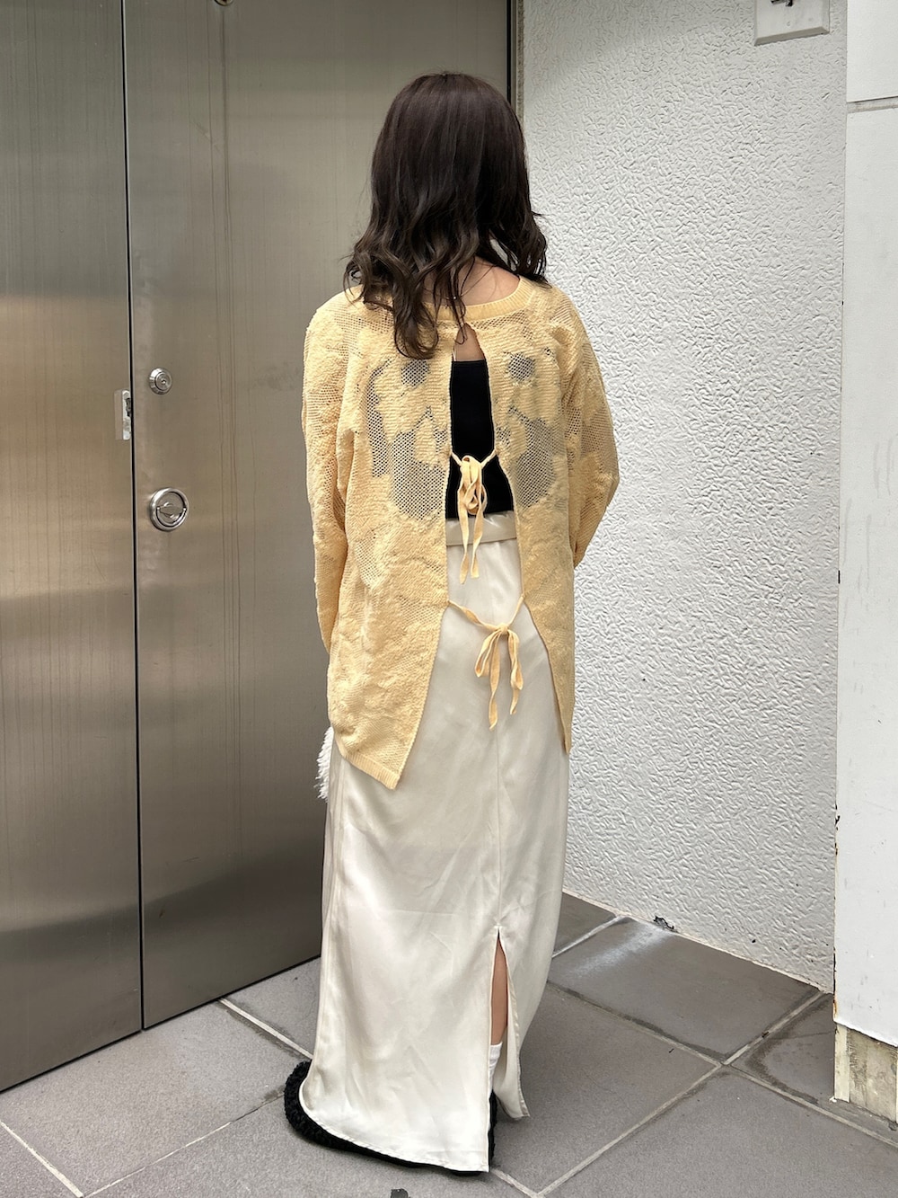 ブラック系のスリッポン、ホワイト系のハンドバッグ、イエロー系のニット/セーターを着用したレディースの冬コーディネートの4枚目の写真