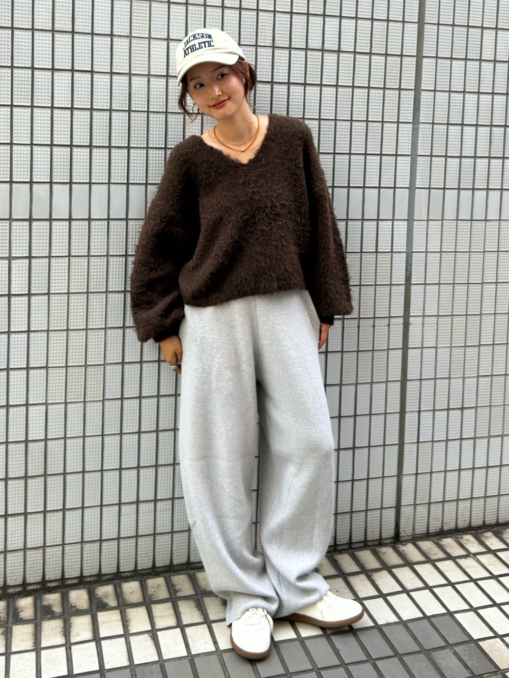 ホワイト系のスニーカー、ブラウン系のニット/セーター、グレー系のその他パンツを着用したレディースの秋コーディネートの2枚目の写真