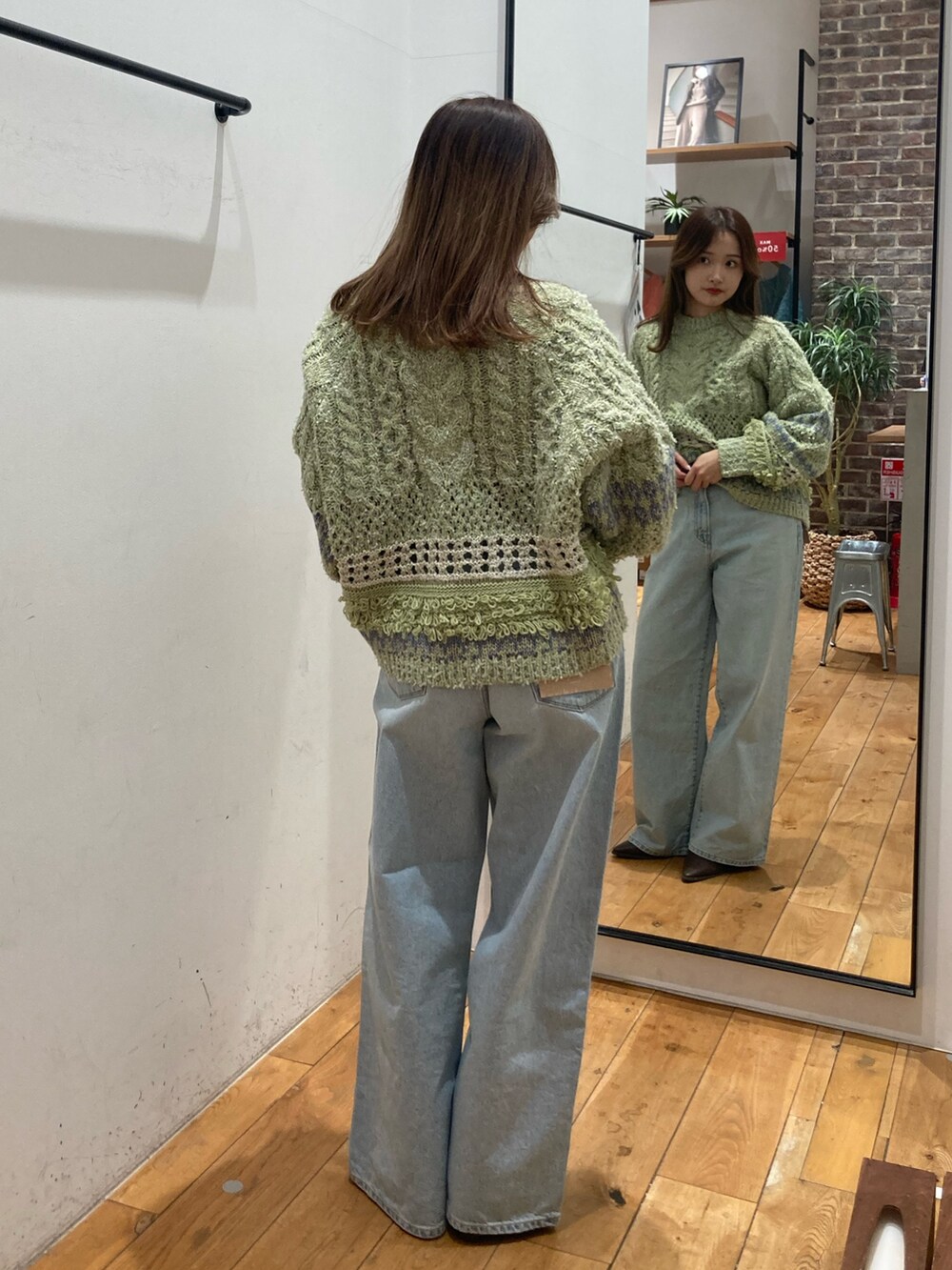 グリーン系のニット/セーター、ブルー系のデニムパンツ、ブラウン系のブーツを着用したレディースの冬コーディネートの4枚目の写真