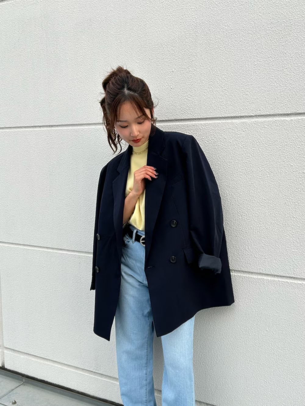 イエロー系のニット/セーター、ブルー系のテーラードジャケット、ブルー系のデニムパンツを着用したレディースの冬コーディネートの7枚目の写真