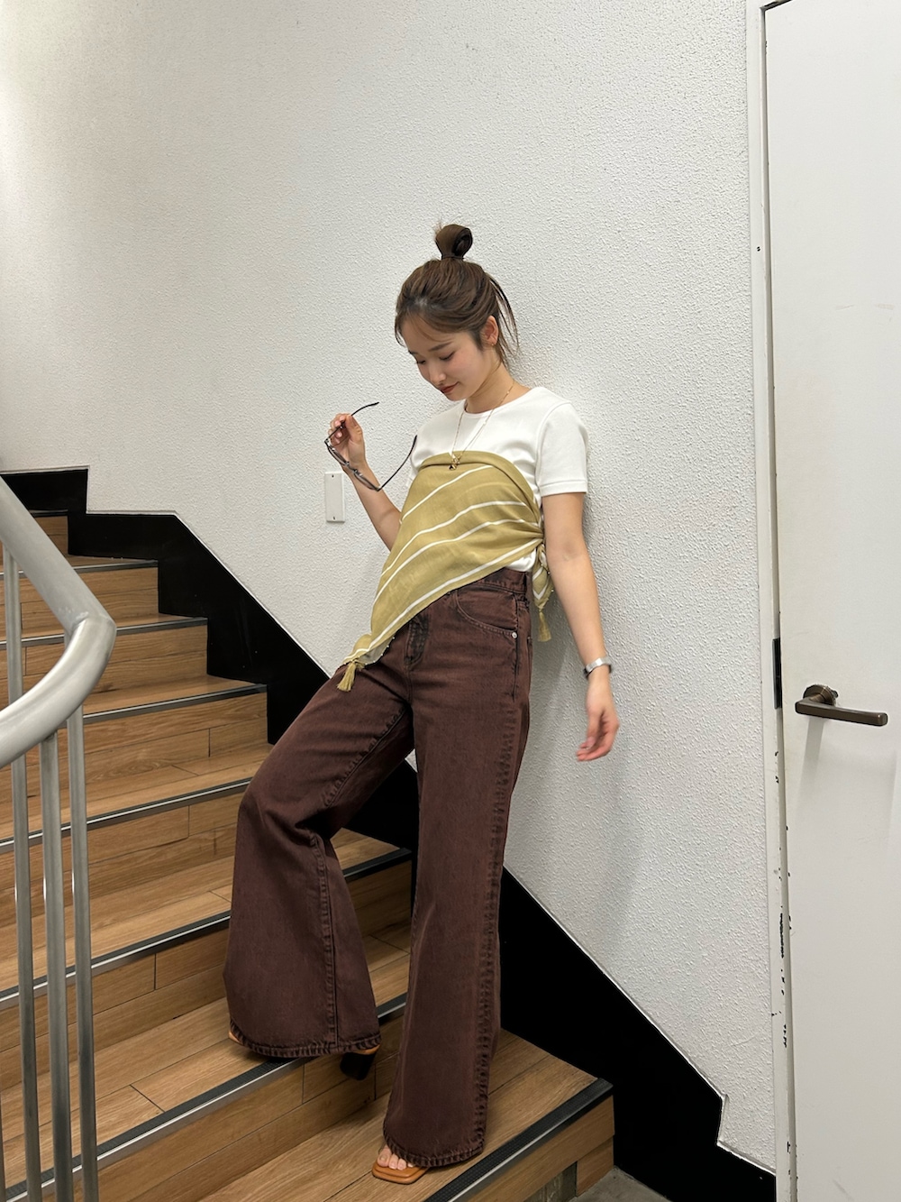 ブラウン系のデニムパンツ、ホワイト系のTシャツ/カットソー、イエロー系のバンダナ/スカーフを着用したレディースの春コーディネートの5枚目の写真