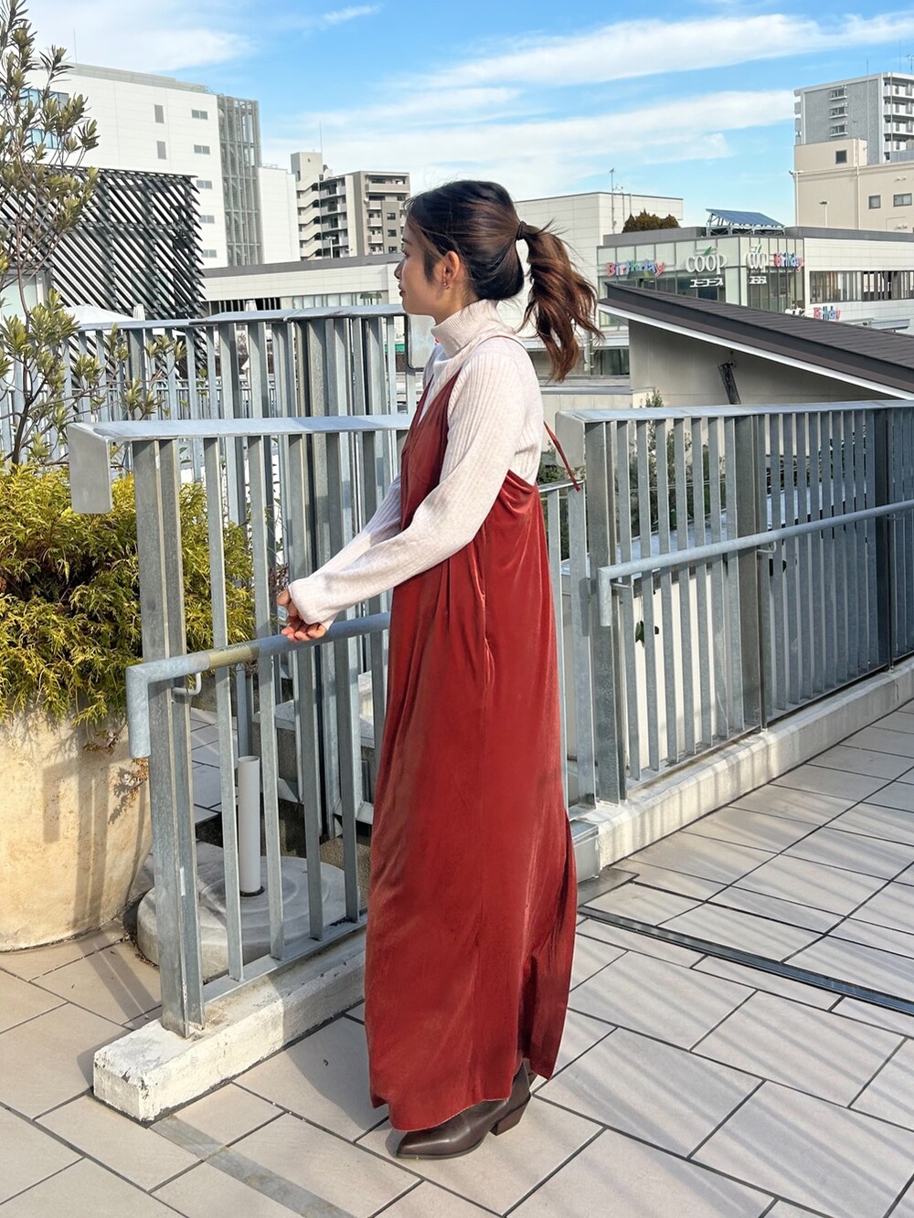 レッド系のワンピース、ホワイト系のニット/セーター、ブラウン系のブーツを着用したレディースの冬コーディネートの2枚目の写真