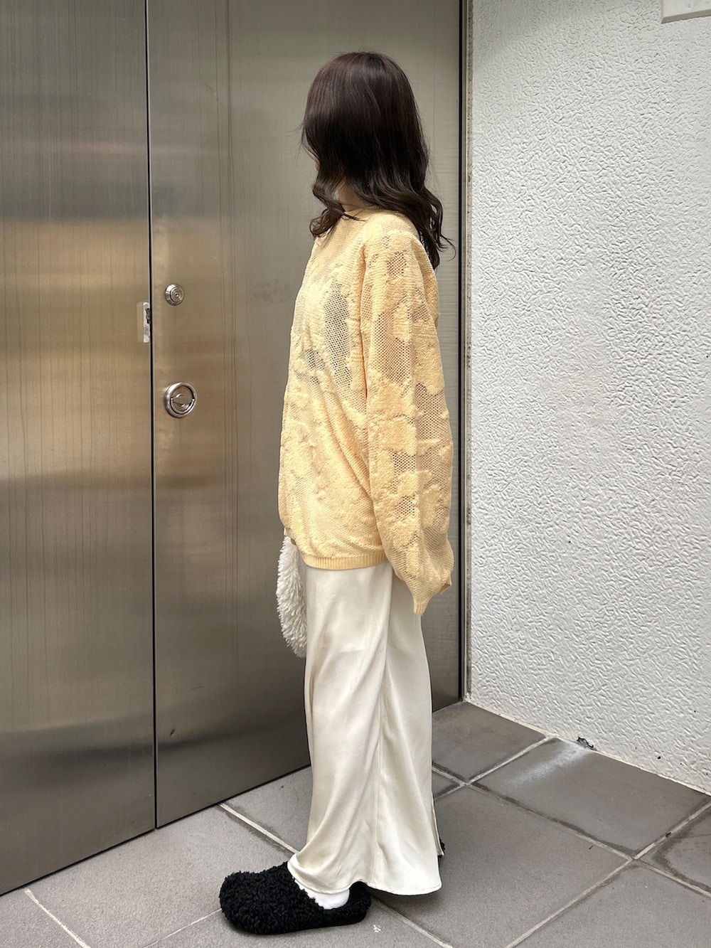 ブラック系のスリッポン、ホワイト系のハンドバッグ、イエロー系のニット/セーターを着用したレディースの冬コーディネートの3枚目の写真