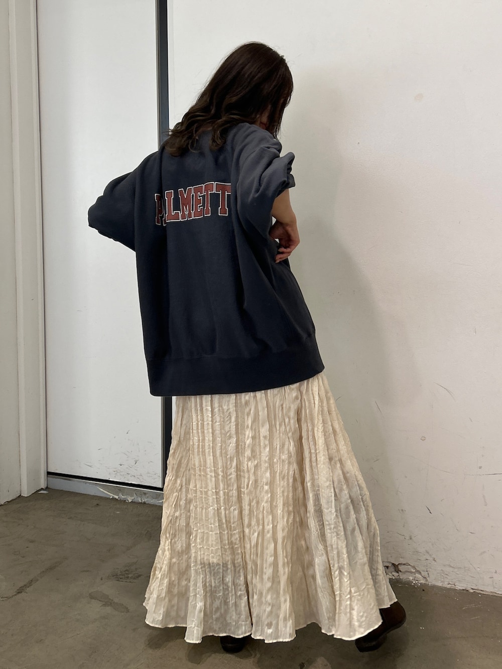 グレー系のスウェット、ホワイト系のスカート、ブラウン系のブーツを着用したレディースの秋コーディネートの2枚目の写真