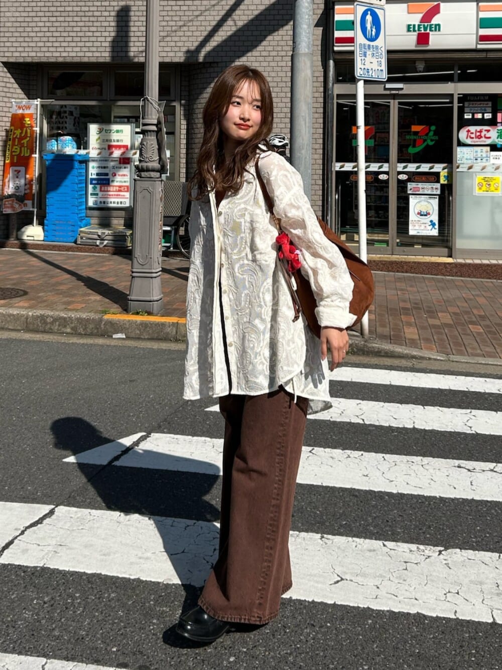 ブラウン系のキャミソール、ホワイト系のシャツ/ブラウス、ブラウン系のデニムパンツを着用したレディースの春コーディネートの4枚目の写真