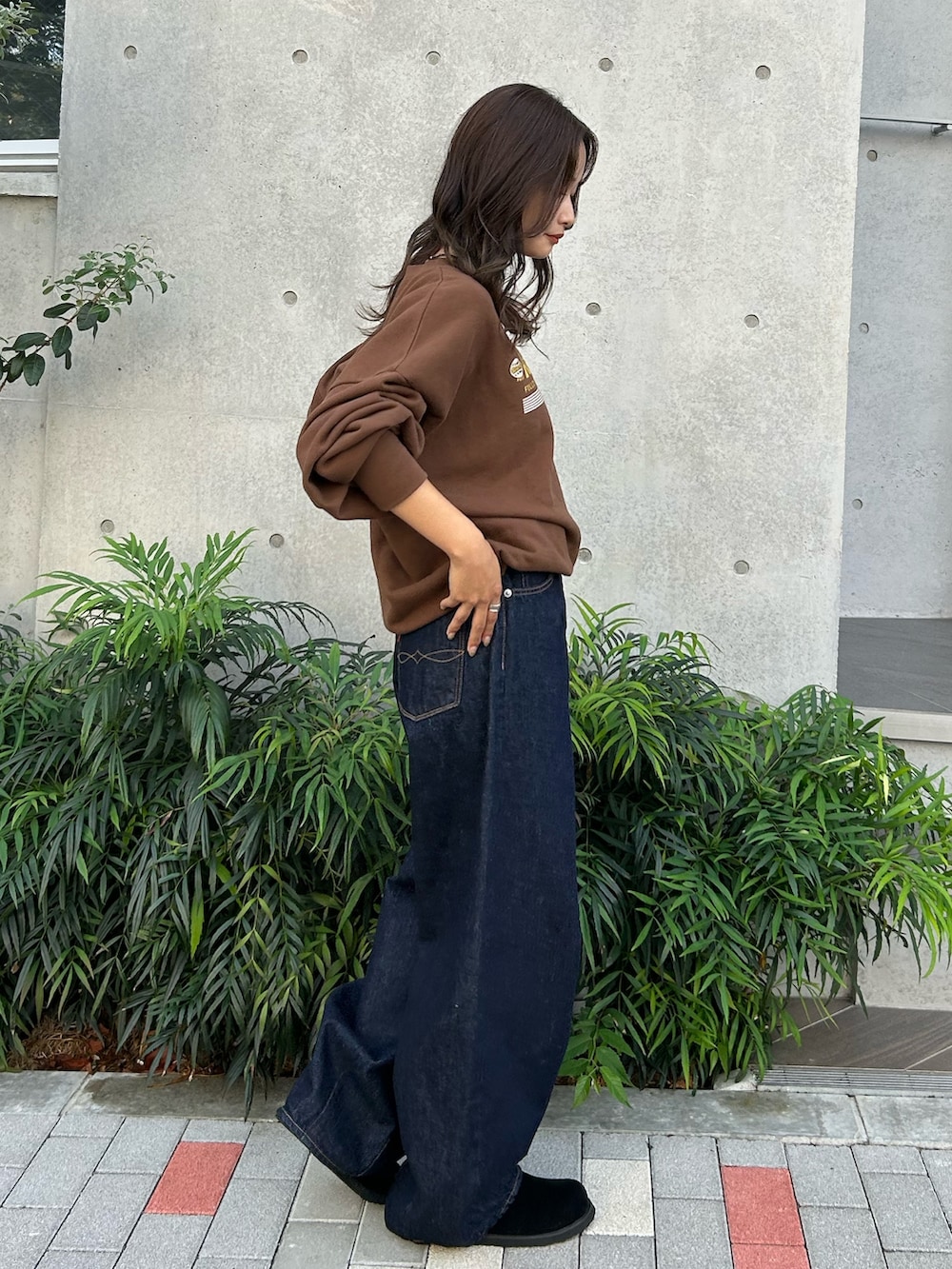 ブルー系のデニムパンツ、ブラック系のスリッポン、ブラウン系のスウェットを着用したレディースの冬コーディネートの5枚目の写真