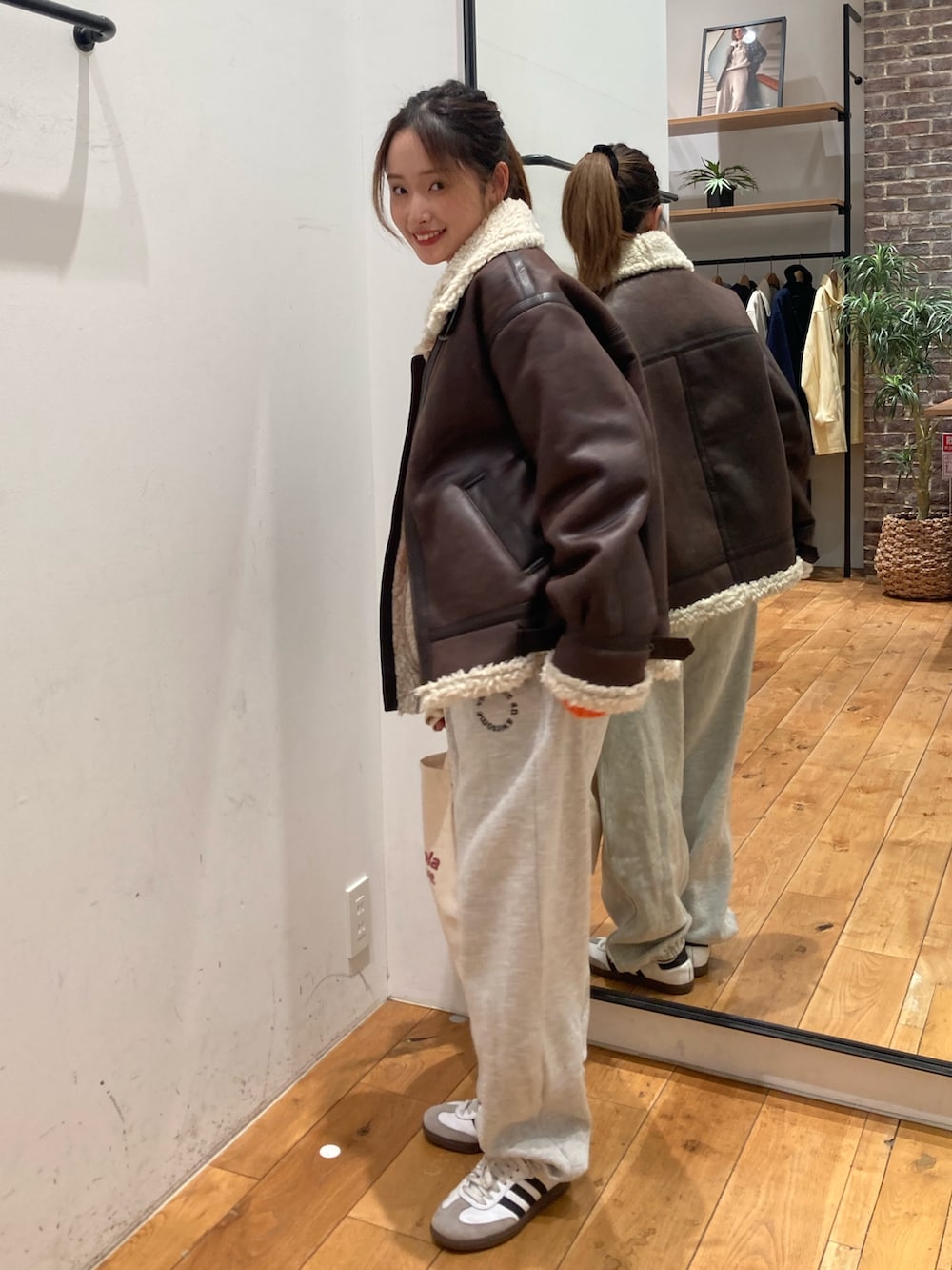 グレー系のスウェットパンツ、レッド系のトートバッグ、ブラウン系のブルゾンを着用したレディースの冬コーディネートの2枚目の写真