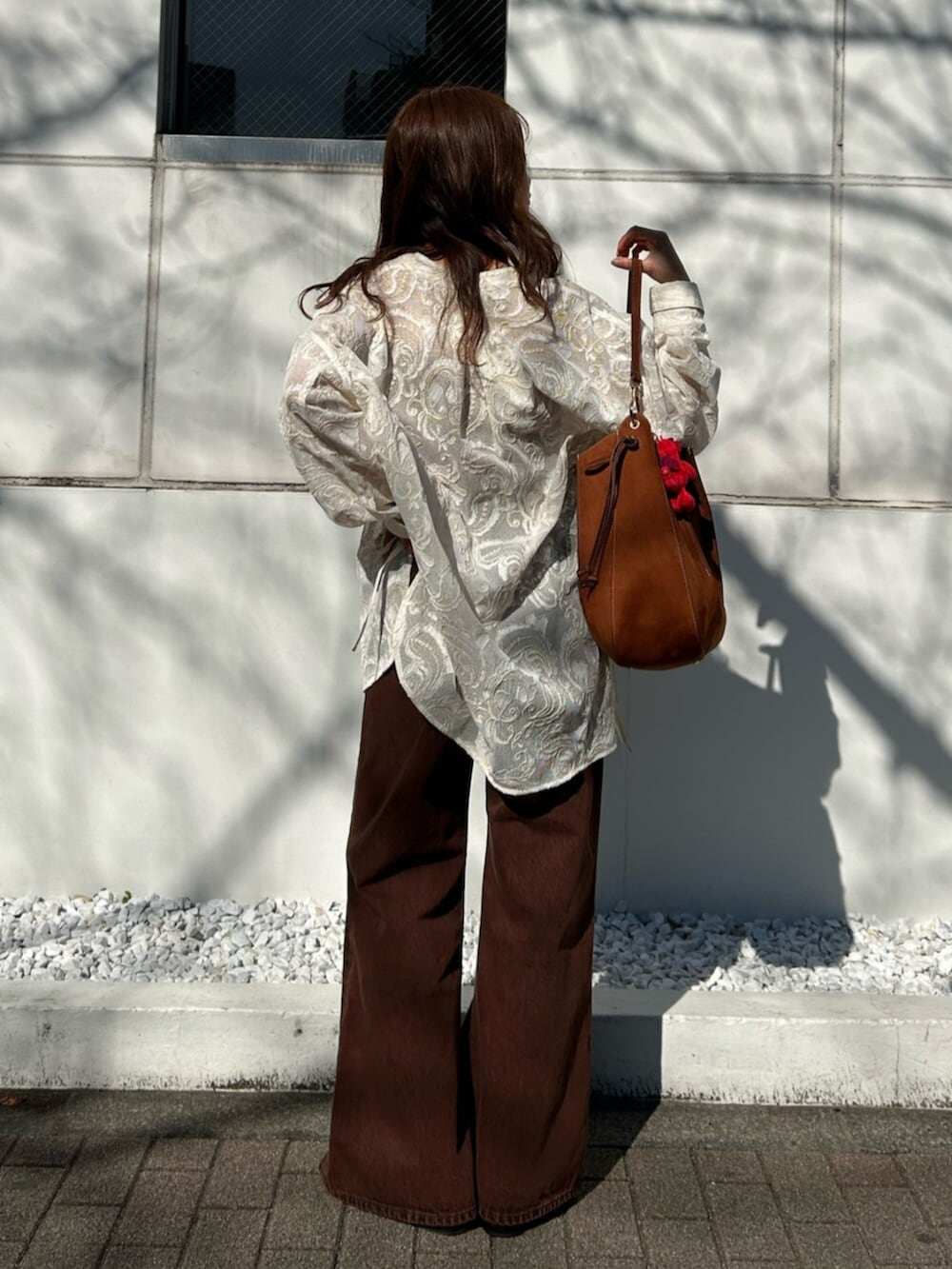 ブラウン系のキャミソール、ホワイト系のシャツ/ブラウス、ブラウン系のデニムパンツを着用したレディースの春コーディネートの9枚目の写真