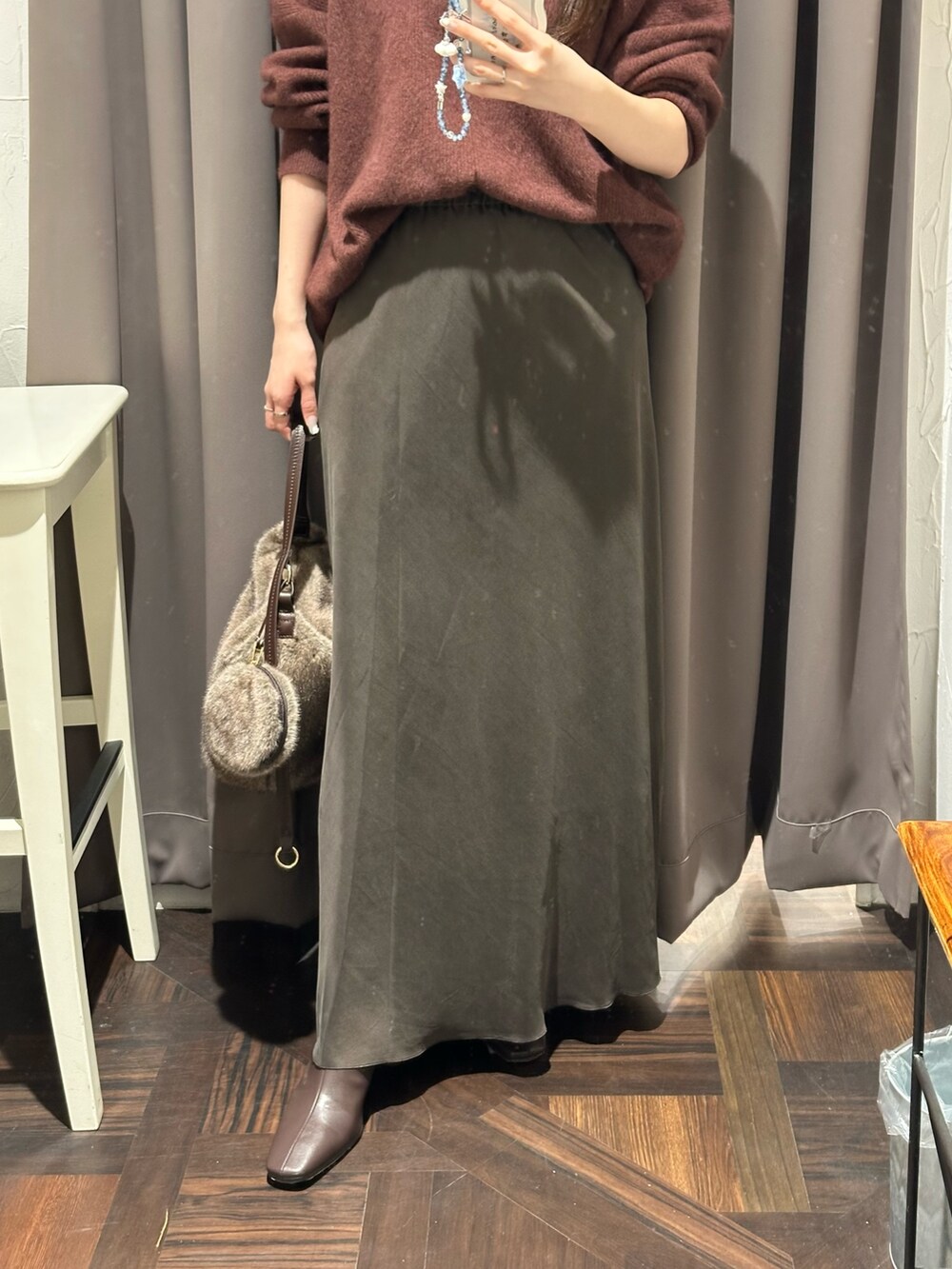 ブラウン系のスカート、レッド系のニット/セーター、ブラウン系のハンドバッグを着用したレディースの秋コーディネートの3枚目の写真