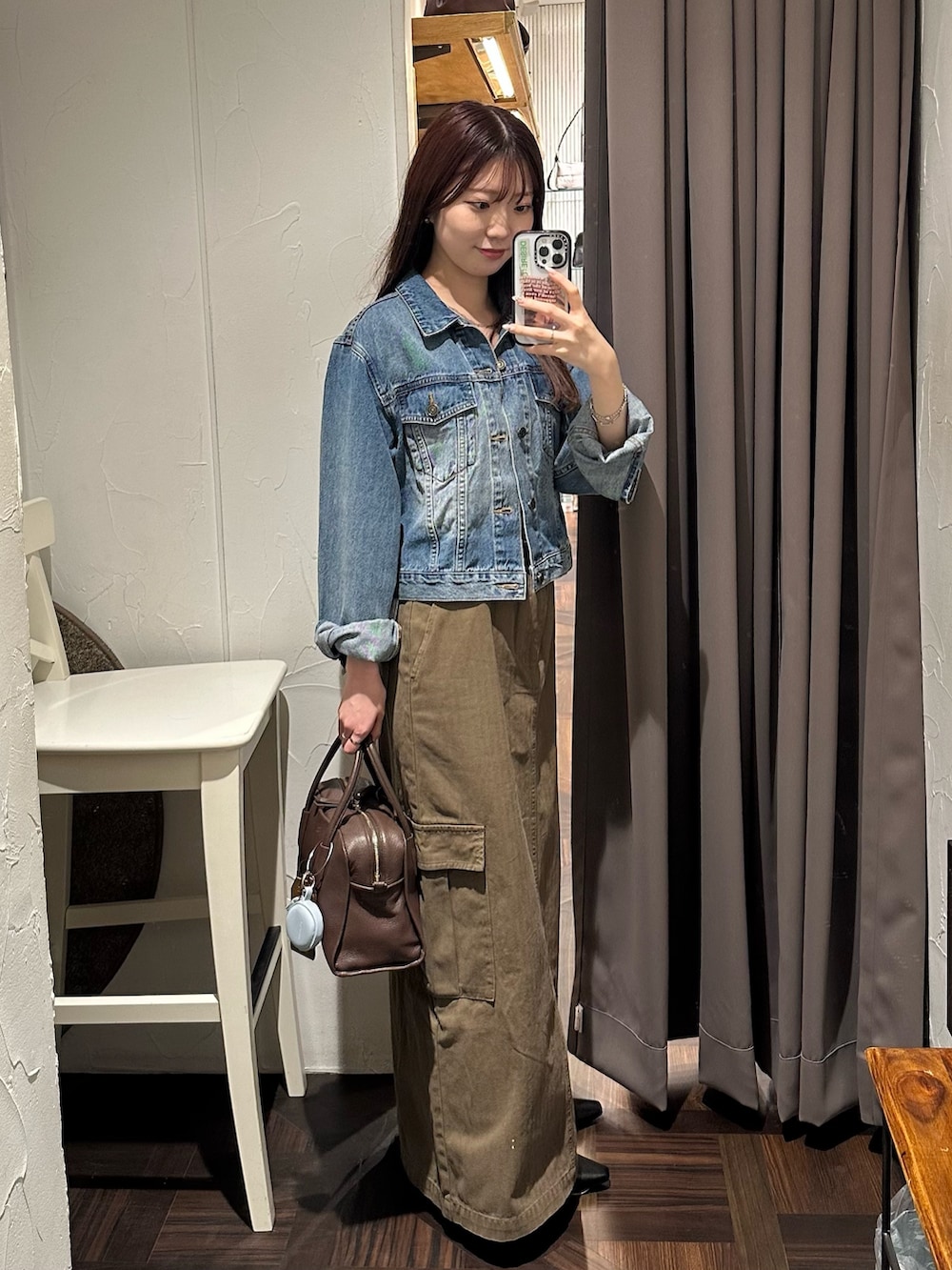 ブラウン系のスカート、ブルー系のデニムジャケット、ブラウン系のボストンバッグを着用したレディースの秋コーディネートの3枚目の写真