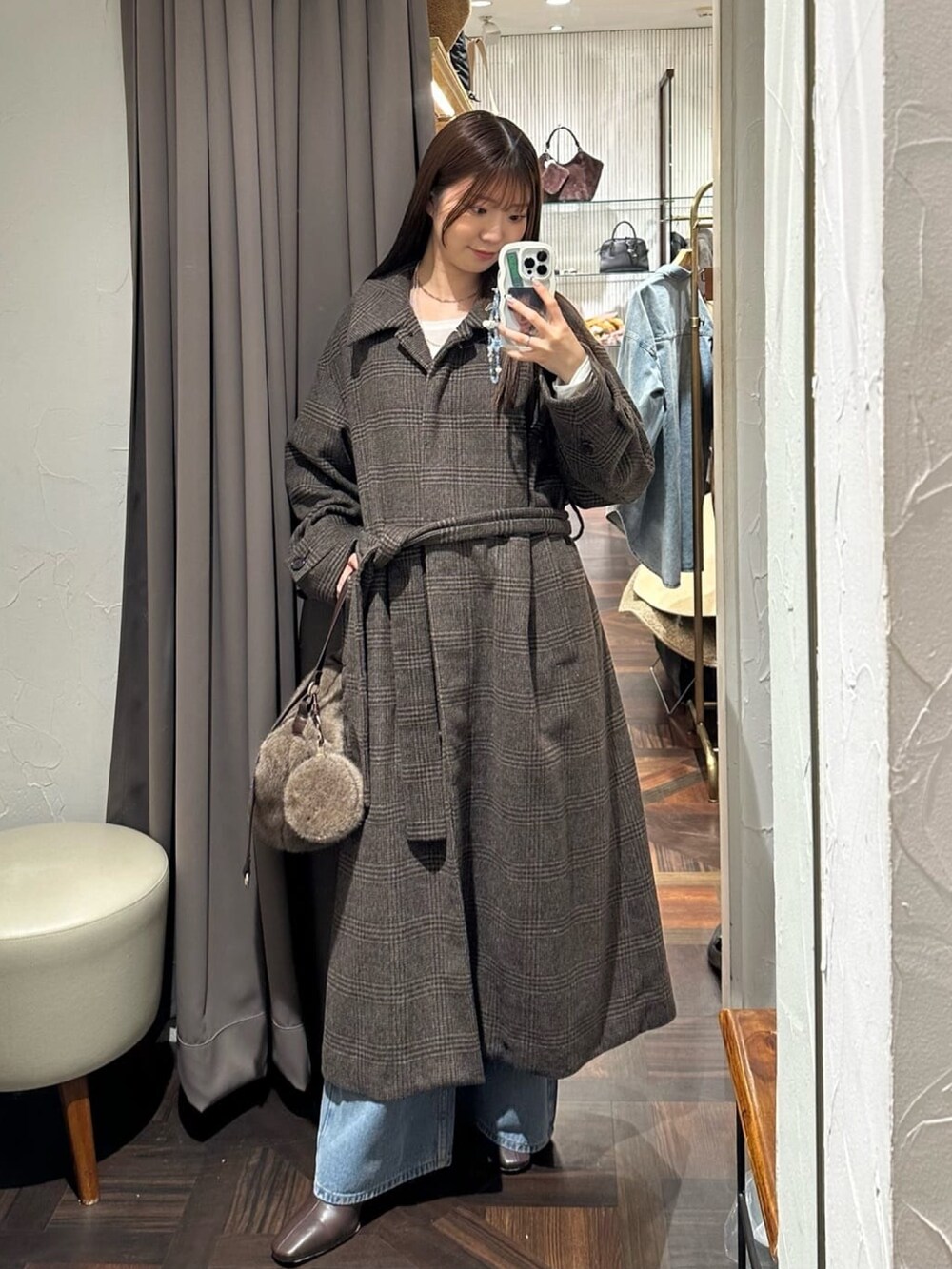 ブラウン系のステンカラーコート、ブルー系のデニムパンツ、ホワイト系のTシャツ/カットソーを着用したレディースの秋コーディネートの3枚目の写真