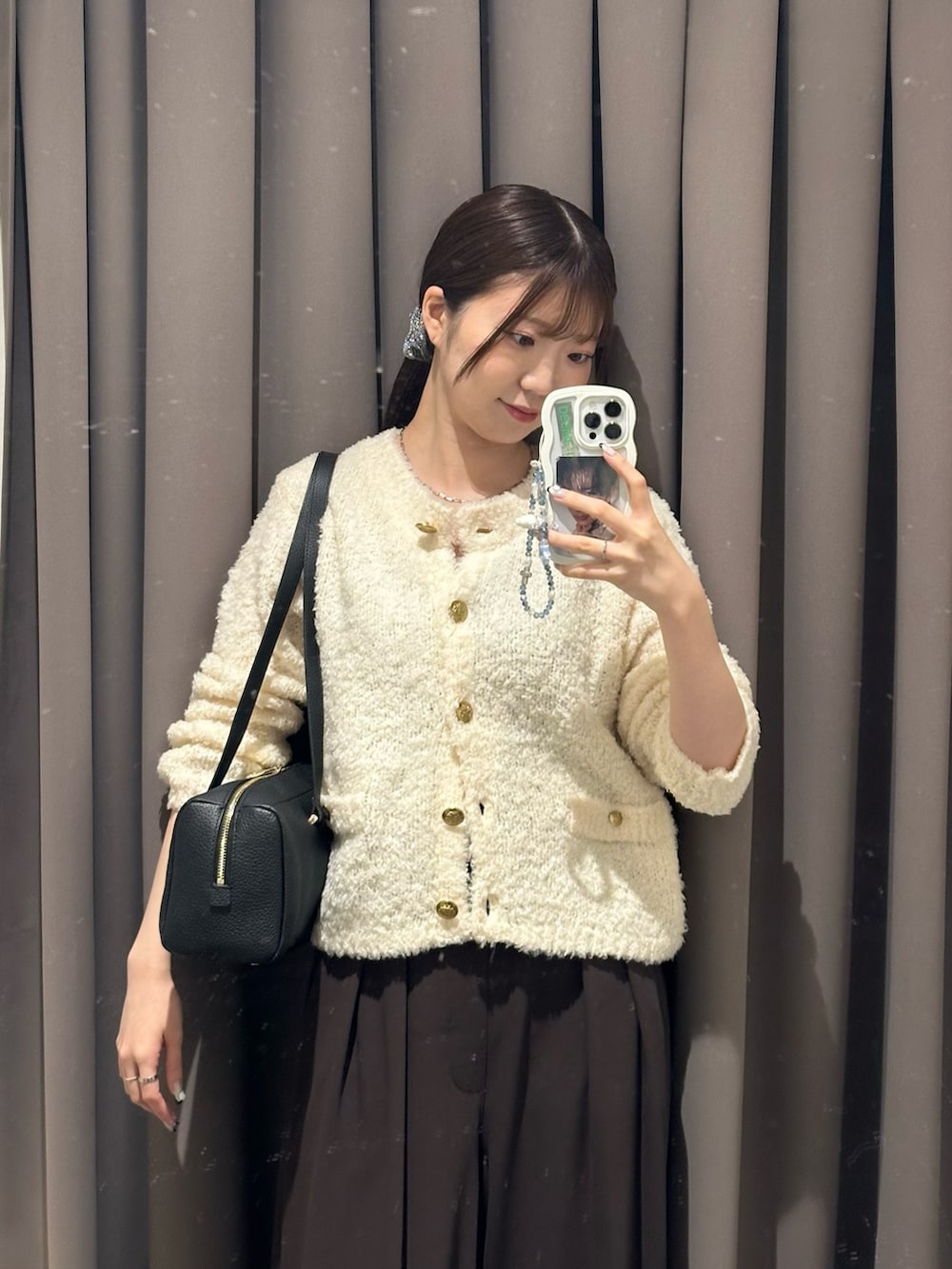 ブラウン系のスラックス、ホワイト系のカーディガン/ボレロ、ブラック系のショルダーバッグを着用したレディースの秋コーディネートの2枚目の写真