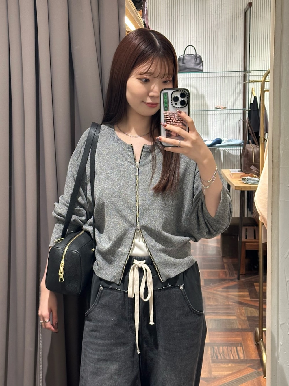 ブラック系のデニムパンツ、ブラック系のカーディガン/ボレロ、ブラック系のパンプスを着用したレディースの秋コーディネートの3枚目の写真