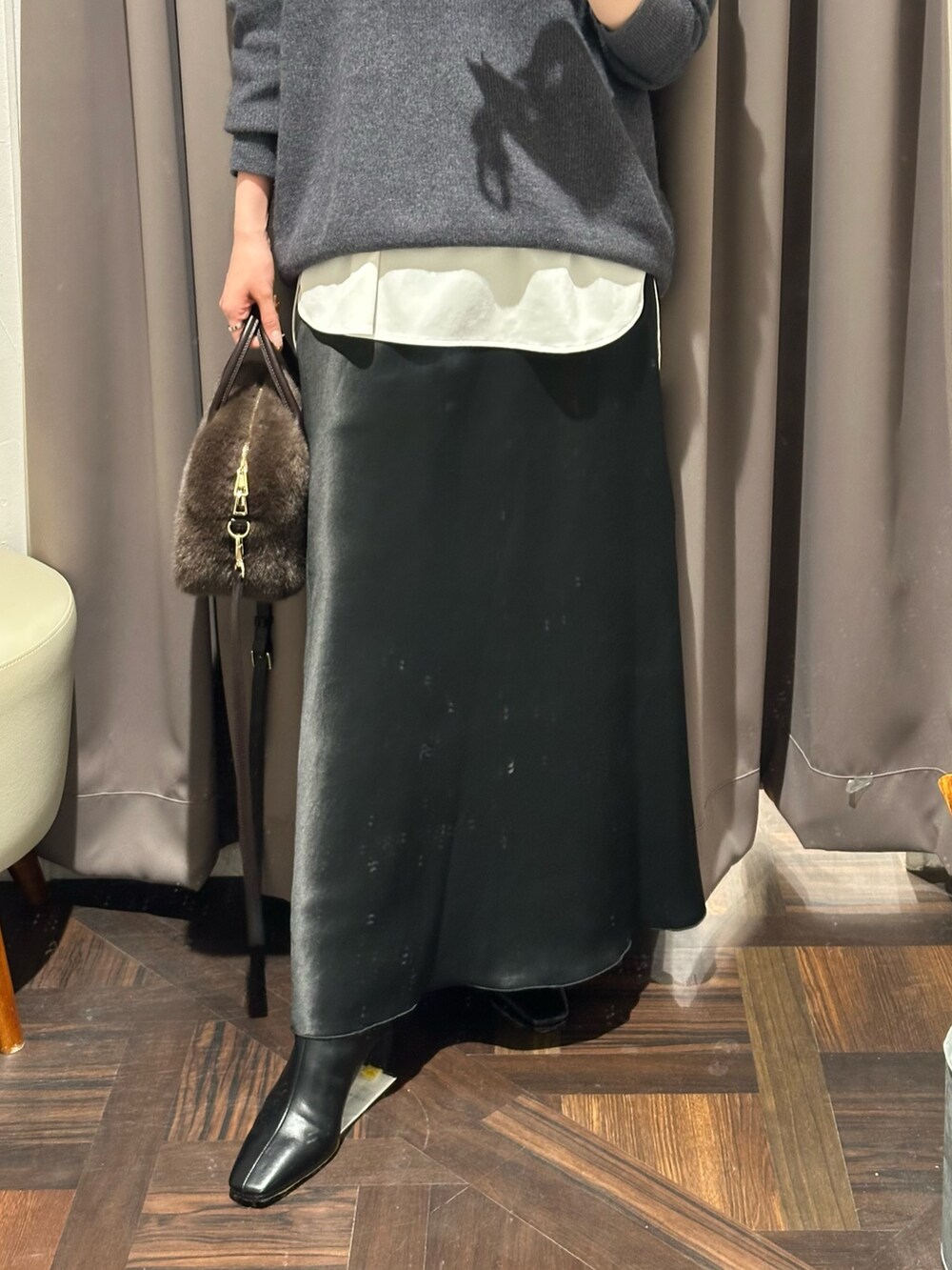 グレー系のニット/セーター、ホワイト系のTシャツ/カットソー、ブラック系のスカートを着用したレディースの冬コーディネートの3枚目の写真