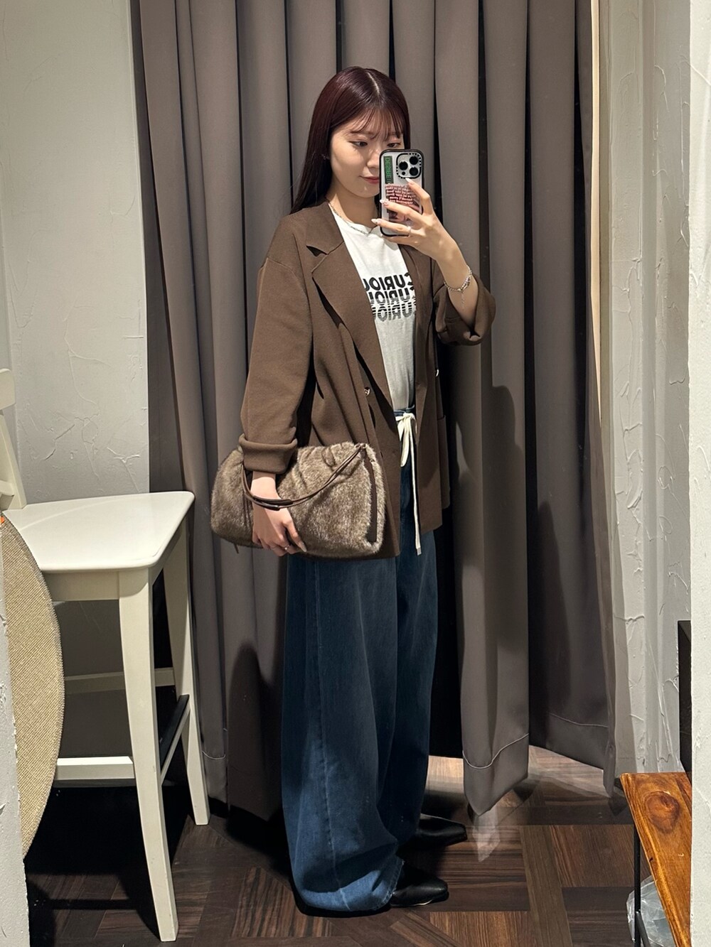 ブルー系のデニムパンツ、ブラウン系のテーラードジャケット、ブラウン系のハンドバッグを着用したレディースの夏コーディネートの4枚目の写真