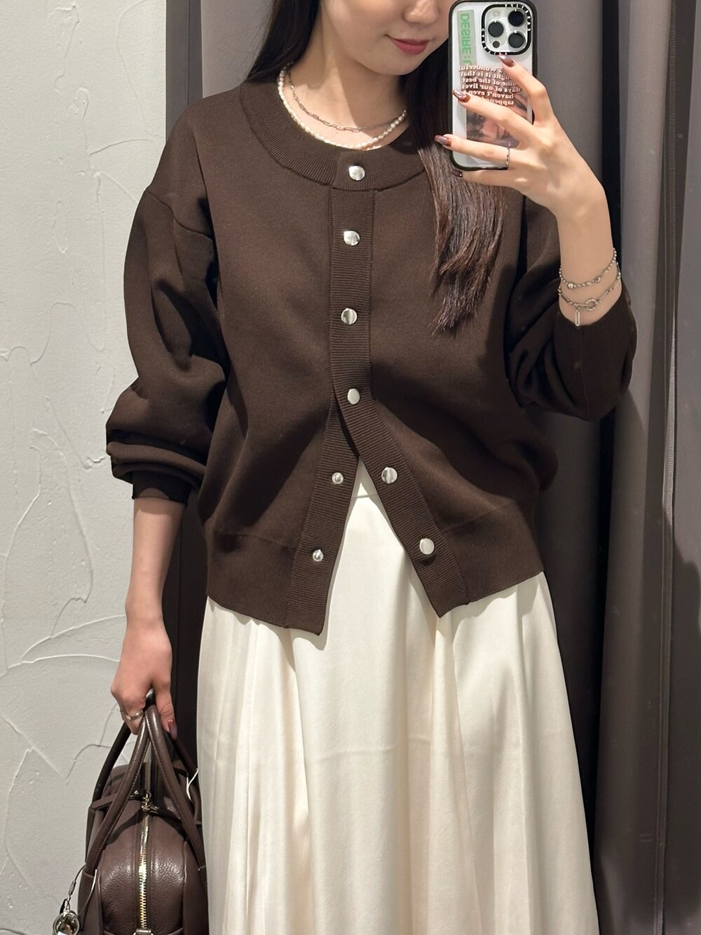 ホワイト系のスカート、ブラウン系のカーディガン/ボレロ、ブラウン系のボストンバッグを着用したレディースの秋コーディネートの2枚目の写真
