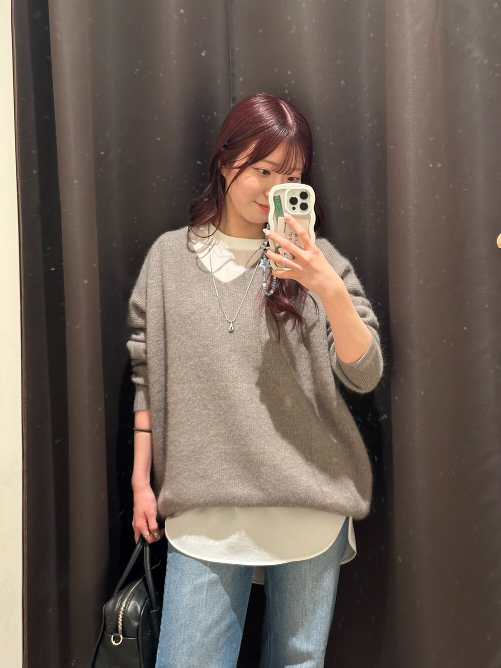 グレー系のニット/セーター、ホワイト系のシャツ/ブラウス、ブルー系のデニムパンツを着用したレディースの冬コーディネートの2枚目の写真