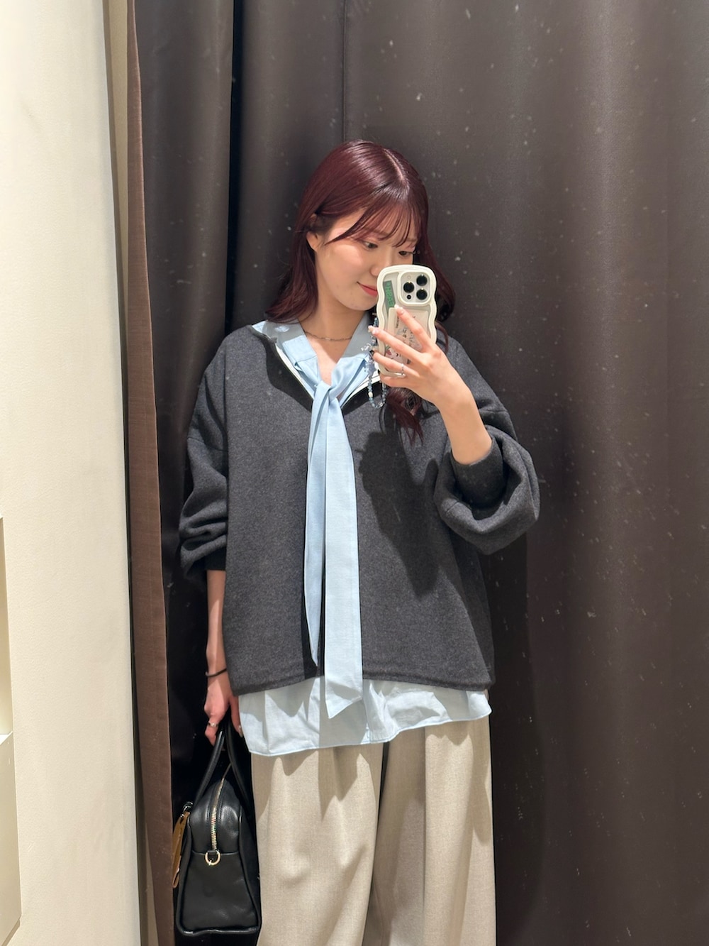 グレー系のニット/セーター、ブルー系のシャツ/ブラウス、ベージュ系のスラックスを着用したレディースの冬コーディネートの2枚目の写真