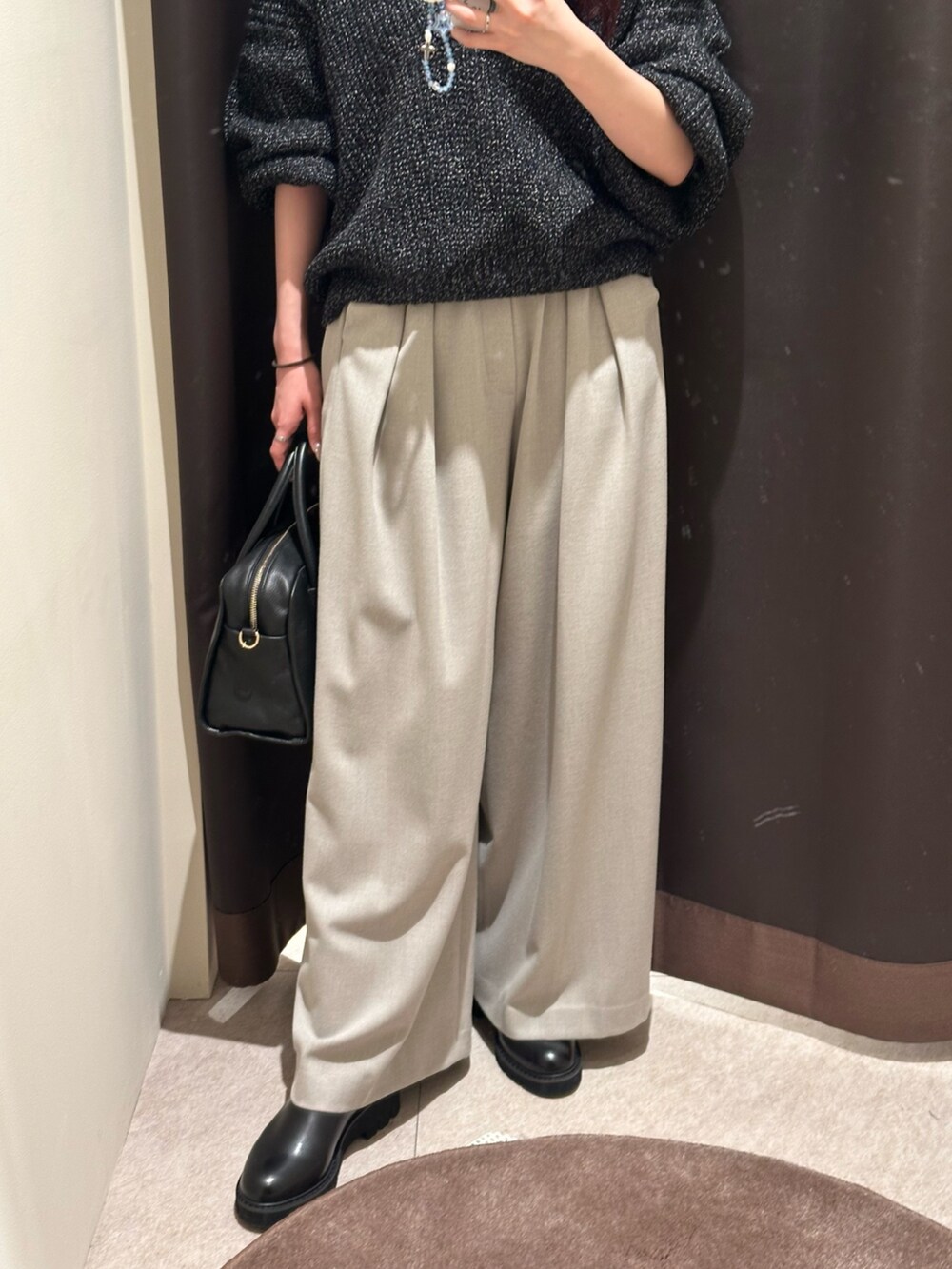 ベージュ系のスラックス、ブラック系のニット/セーター、ブラック系のブーツを着用したレディースの冬コーディネートの3枚目の写真