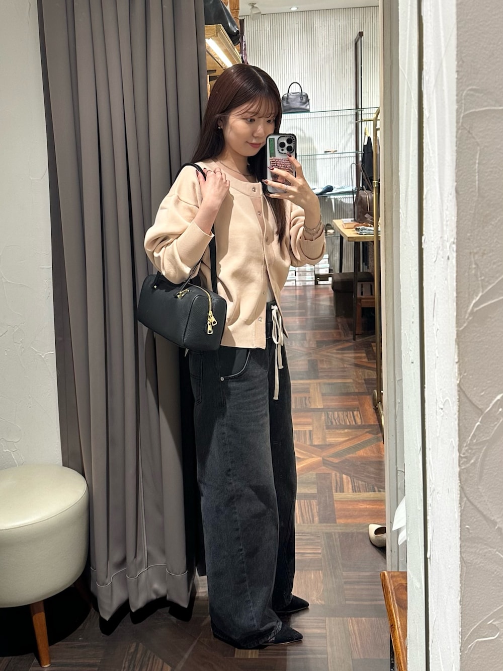 ブラック系のデニムパンツ、ピンク系のカーディガン/ボレロ、ブラック系のショルダーバッグを着用したレディースの秋コーディネートの3枚目の写真