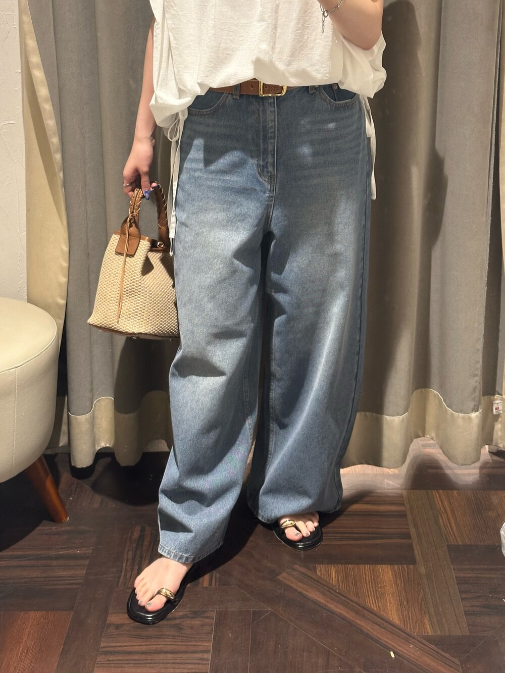 ブルー系のデニムパンツ、ホワイト系のシャツ/ブラウス、ブラウン系のハンドバッグを着用したレディースの夏コーディネートの3枚目の写真