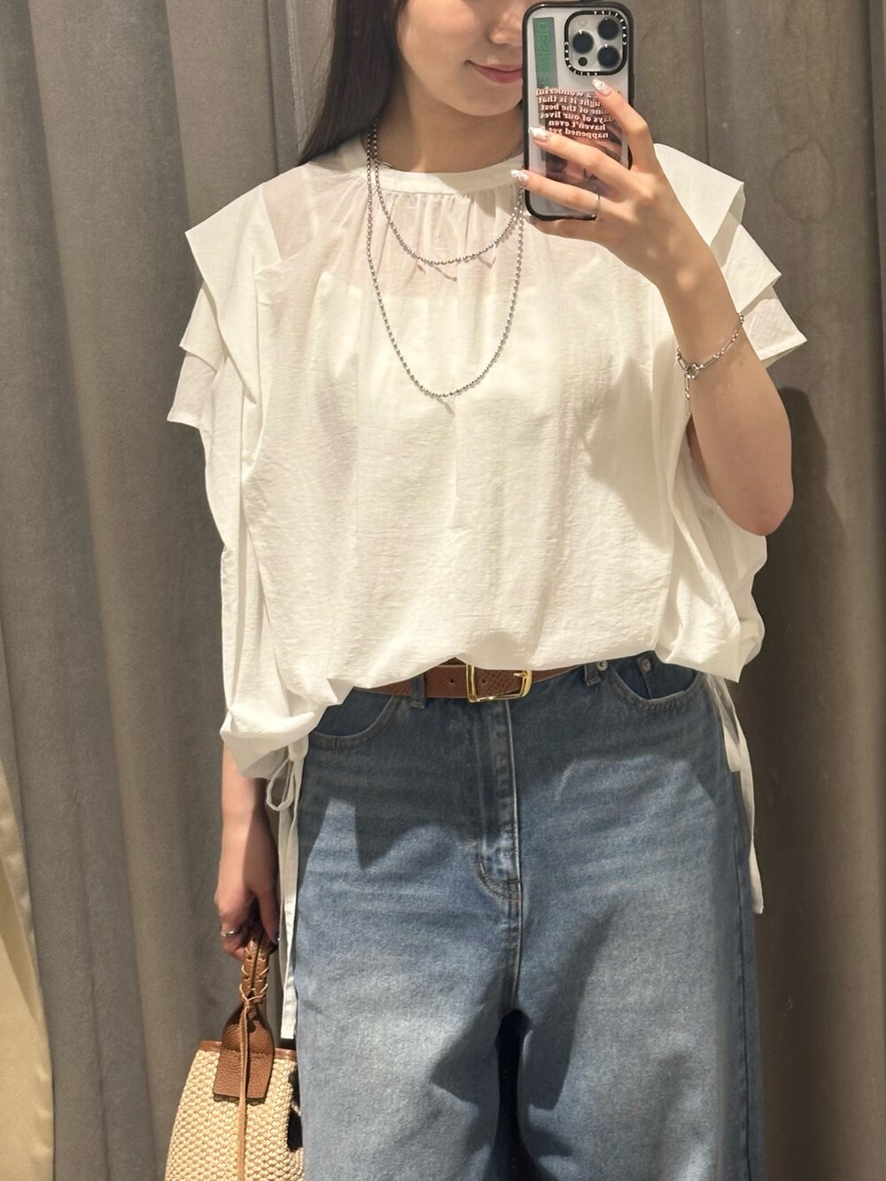 ブルー系のデニムパンツ、ホワイト系のシャツ/ブラウス、ブラウン系のハンドバッグを着用したレディースの夏コーディネートの2枚目の写真