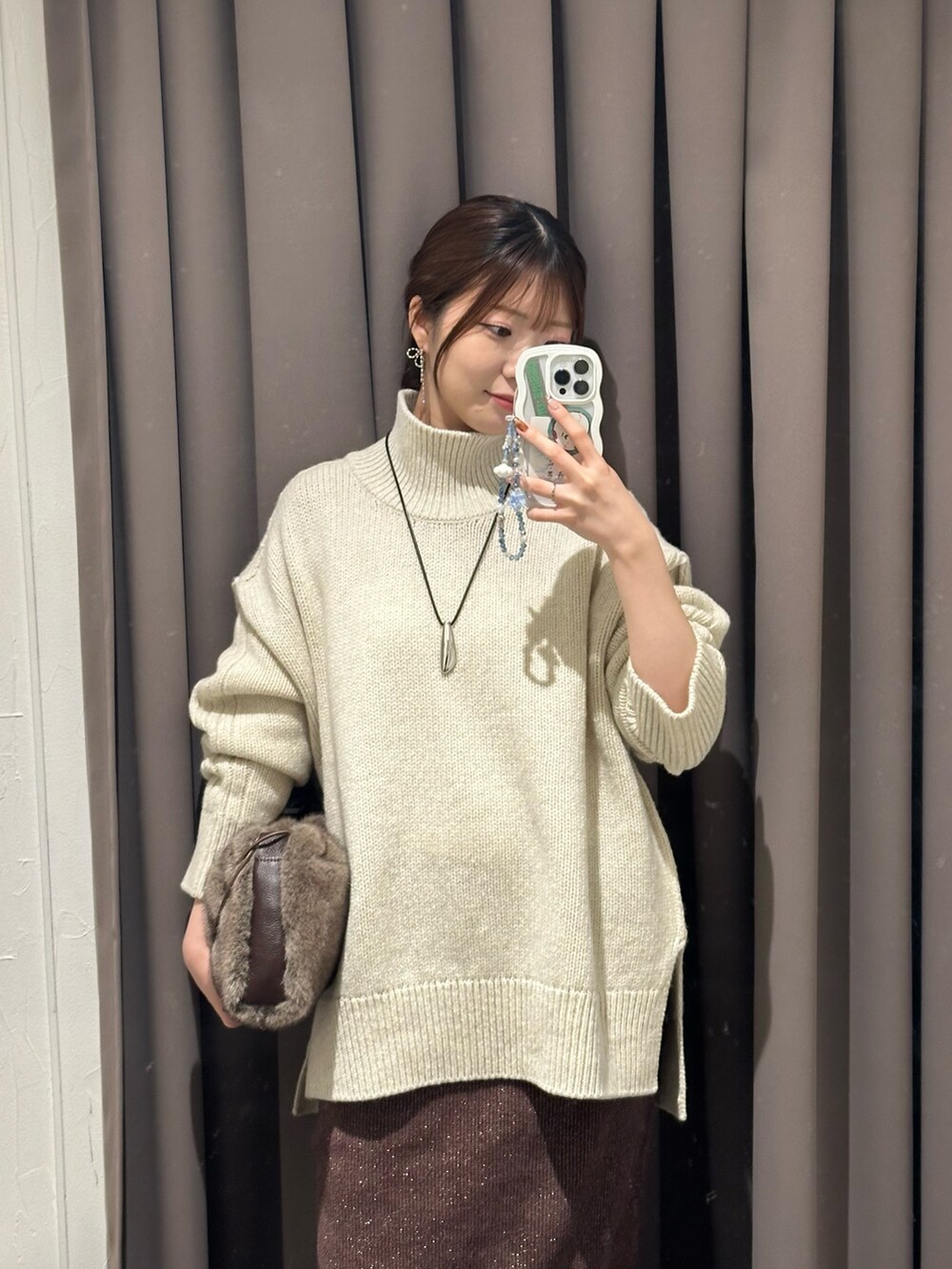 ブラウン系のスカート、ブラック系のブーツ、ブラウン系のハンドバッグを着用したレディースの秋コーディネートの2枚目の写真