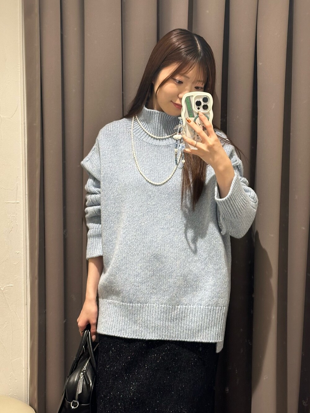 ブルー系のニット/セーター、ブラック系のスカート、ブラック系のブーツを着用したレディースの秋コーディネートの2枚目の写真