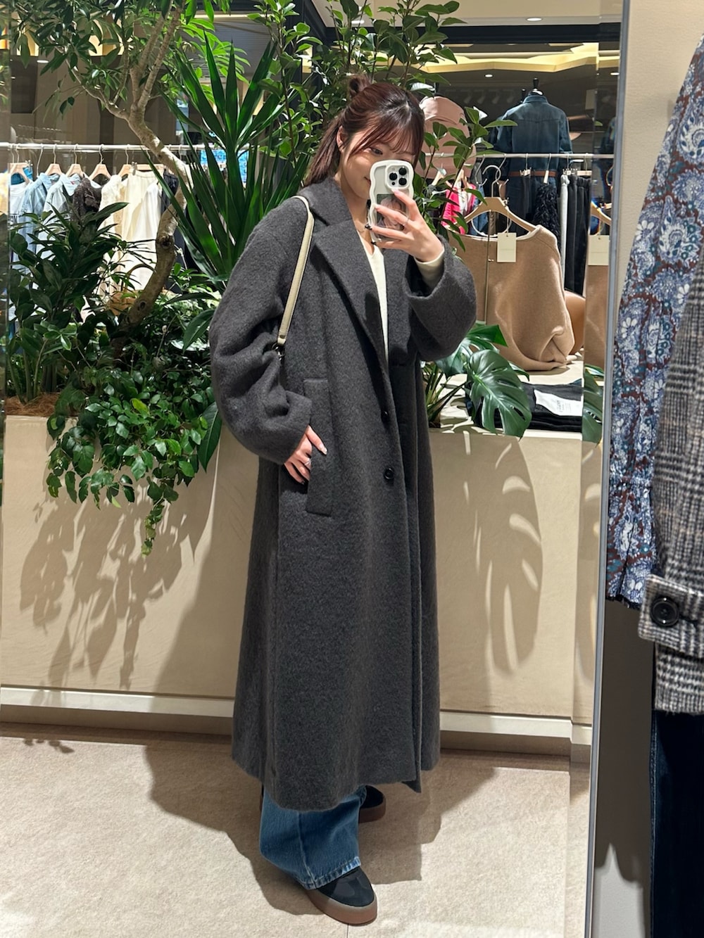 ホワイト系のニット/セーター、ブルー系のデニムパンツ、ブラウン系のチェスターコートを着用したレディースの冬コーディネートの4枚目の写真