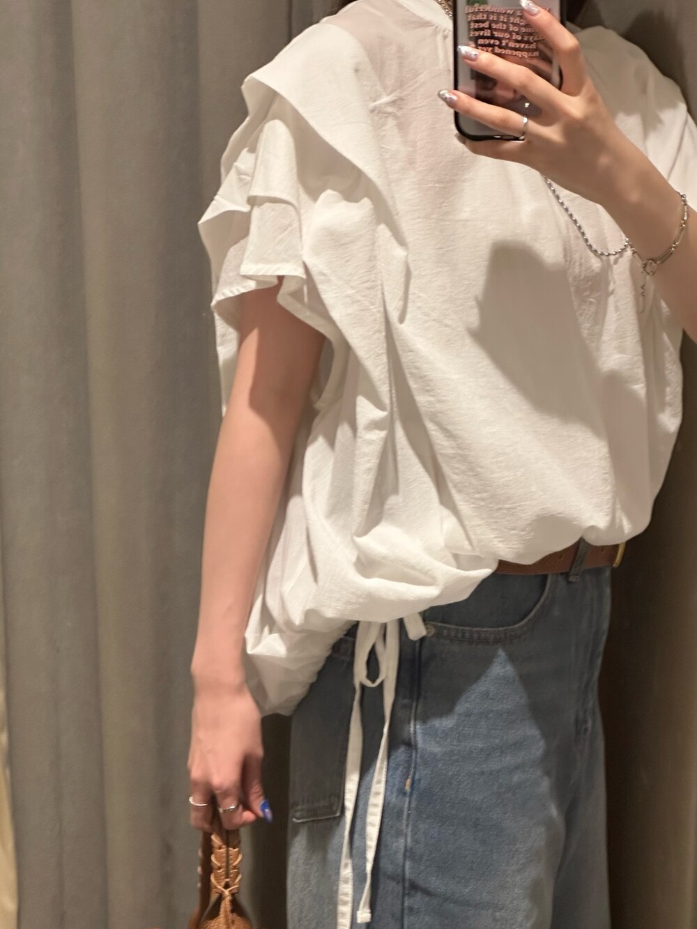 ブルー系のデニムパンツ、ホワイト系のシャツ/ブラウス、ブラウン系のハンドバッグを着用したレディースの夏コーディネートの5枚目の写真