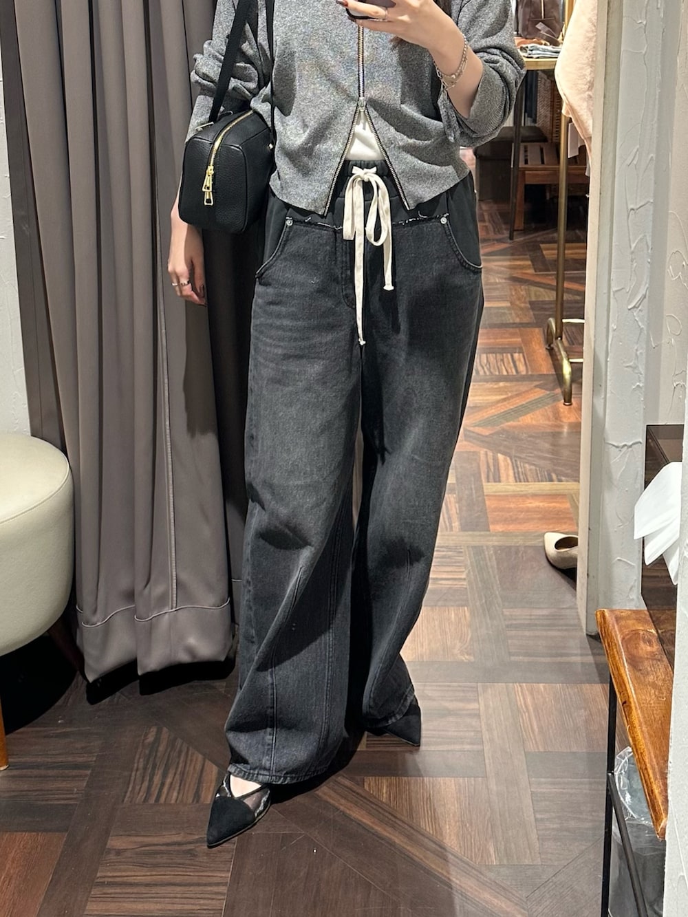 ブラック系のデニムパンツ、ブラック系のカーディガン/ボレロ、ブラック系のパンプスを着用したレディースの秋コーディネートの2枚目の写真