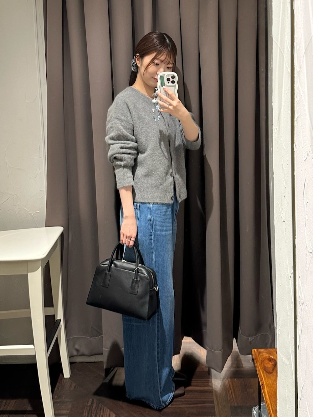 ブルー系のデニムパンツ、グレー系のカーディガン/ボレロ、ブラック系のボストンバッグを着用したレディースの秋コーディネートの3枚目の写真